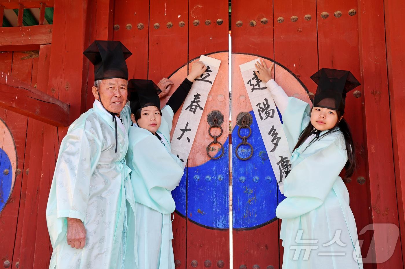 본문 이미지 - 24절기 중 첫 절기이자 봄의 시작을 알리는 입춘(立春·2월 4일)을 맞이해 지난 2일 충북 괴산군 연풍향교 외삼문에 유림과 어린이들이 군민의 무사 안녕과 한 해의 복을 기원하는 입춘첩을 붙이고 있다.(괴산군 제공).2026.2.3/뉴스1 