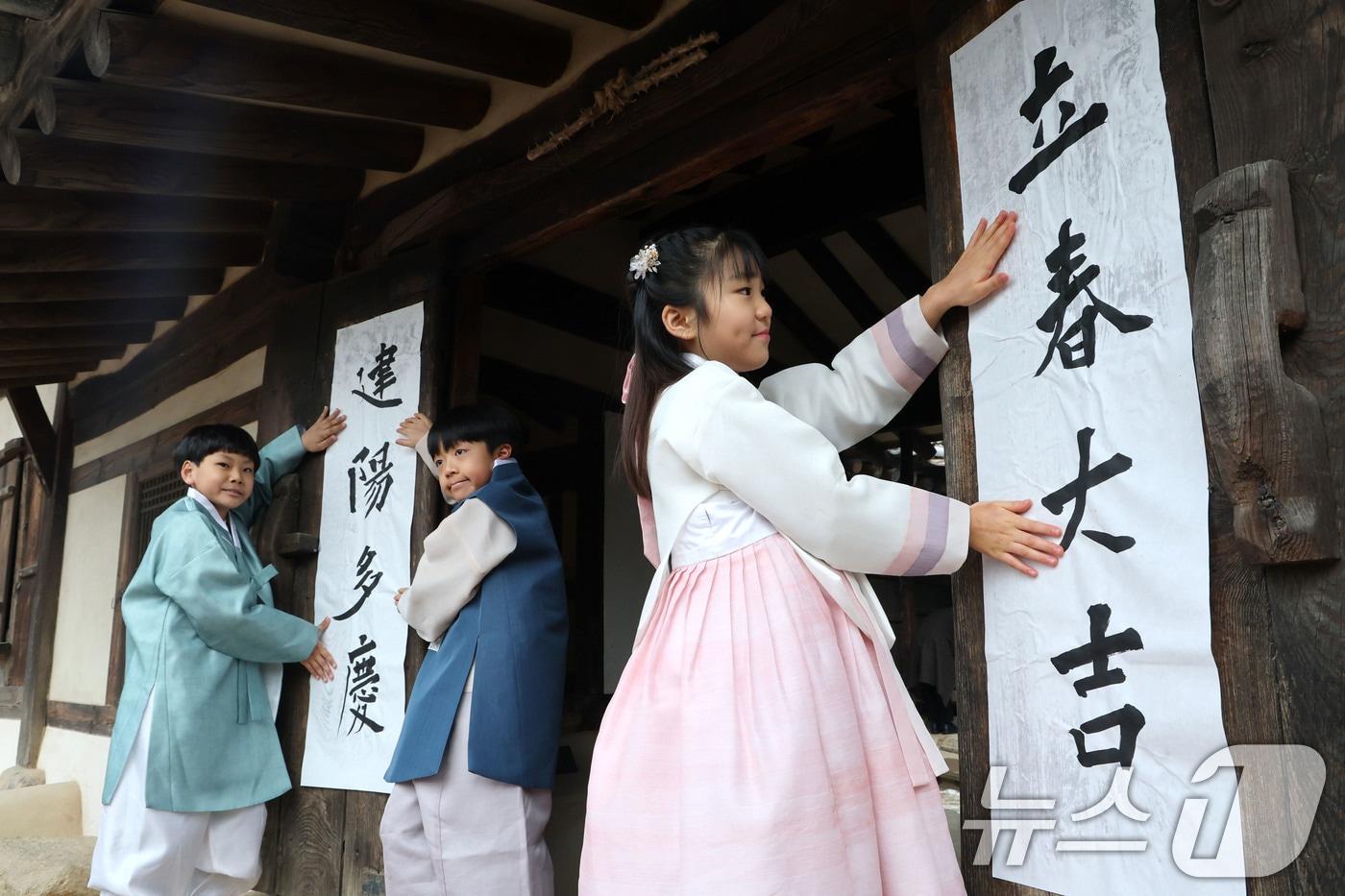 본문 이미지 - 봄의 시작을 알리는 입춘(立春)인 4일 서울 종로구 삼청동 국립민속박물관내 전통한옥인 오촌댁 대문에 어린이들이 '입춘대길(立春大吉)'과 '건양다경(建陽多慶)' 글귀를 담은 입춘첩을 붙이고 있다. 입춘첩은 봄의 희망을 담아 한 해 동안 길한 운과 경사스러움이 가득하기를 기원하고 풍년을 기원하는 세시풍속으로 대문이나 문설주에 붙인다. 2026.2.4/뉴스1 ⓒ News1 이광호 기자