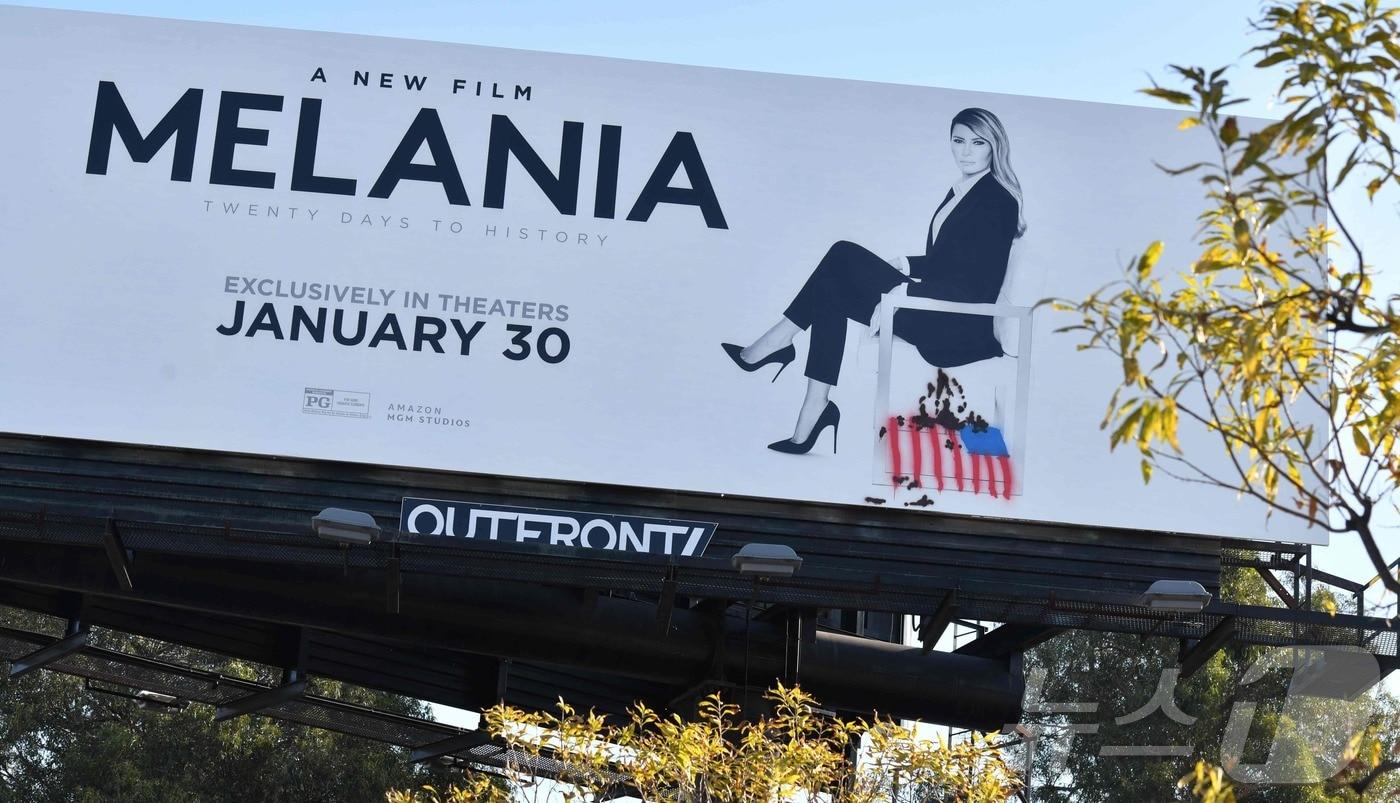 본문 이미지 - 2026년 1월30일(현지시간) 미국 캘리포니아 컬버시티에 걸린 다큐멘터리 '멜라니아'의 홍보판. 활동가 예술 집단 ‘인디클라인(INDECLINE)’이 멜라니아 밑에 불타는 미국 국기 그래피티를 그려넣었다. 2026.01.30.ⓒ AFP=뉴스1