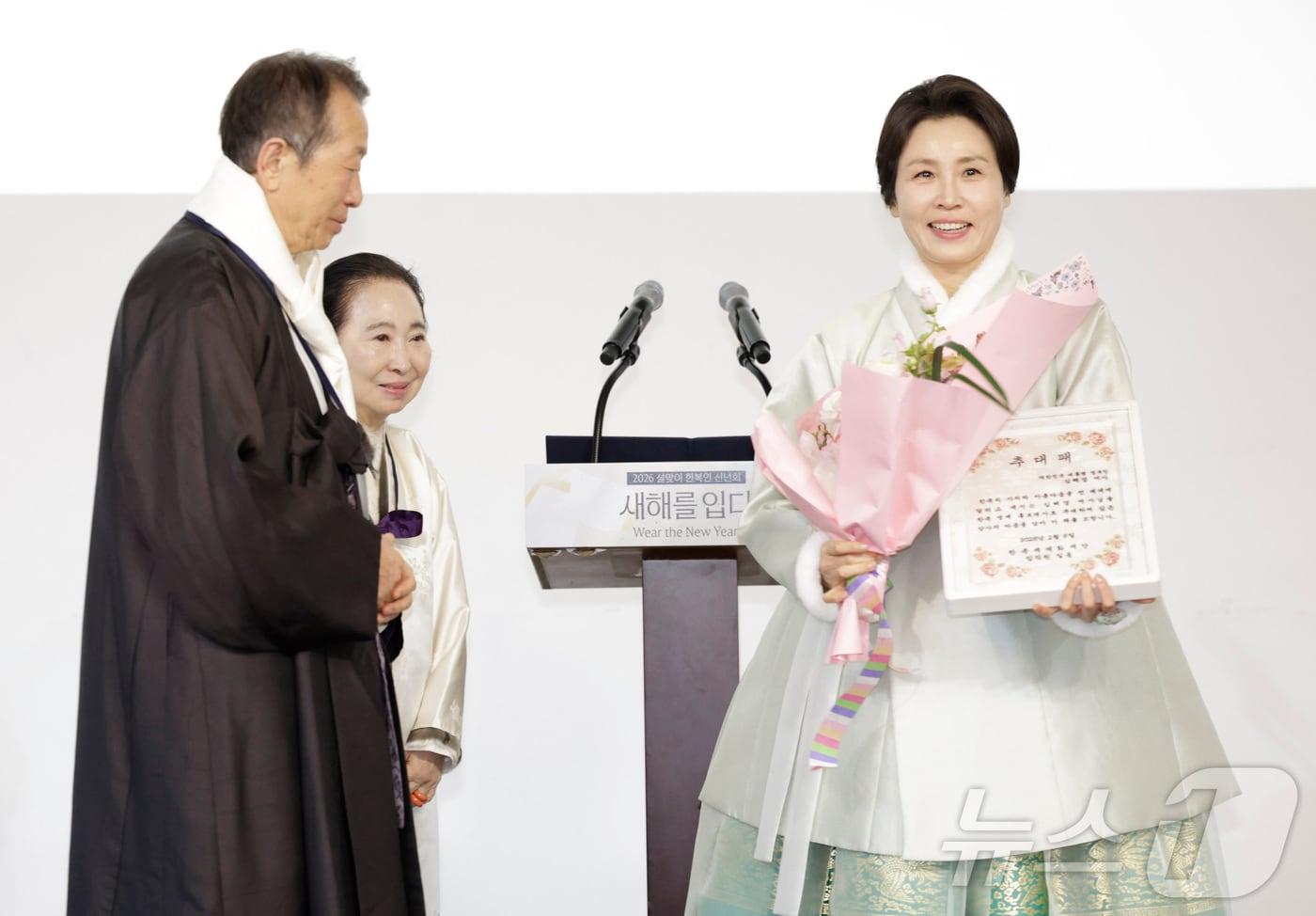 본문 이미지 - 김혜경 여사가 6일 서울 중구 정동1928 아트센터에서 열린 2026 설맞이 한복인 신년회에서 정순훈 한복세계화재단 이사장으로부터 한복 명예홍보대사 추대패를 전달받고 있다. (청와대통신사진기자단) 2026.2.6 / ⓒ 뉴스1 이재명 기자