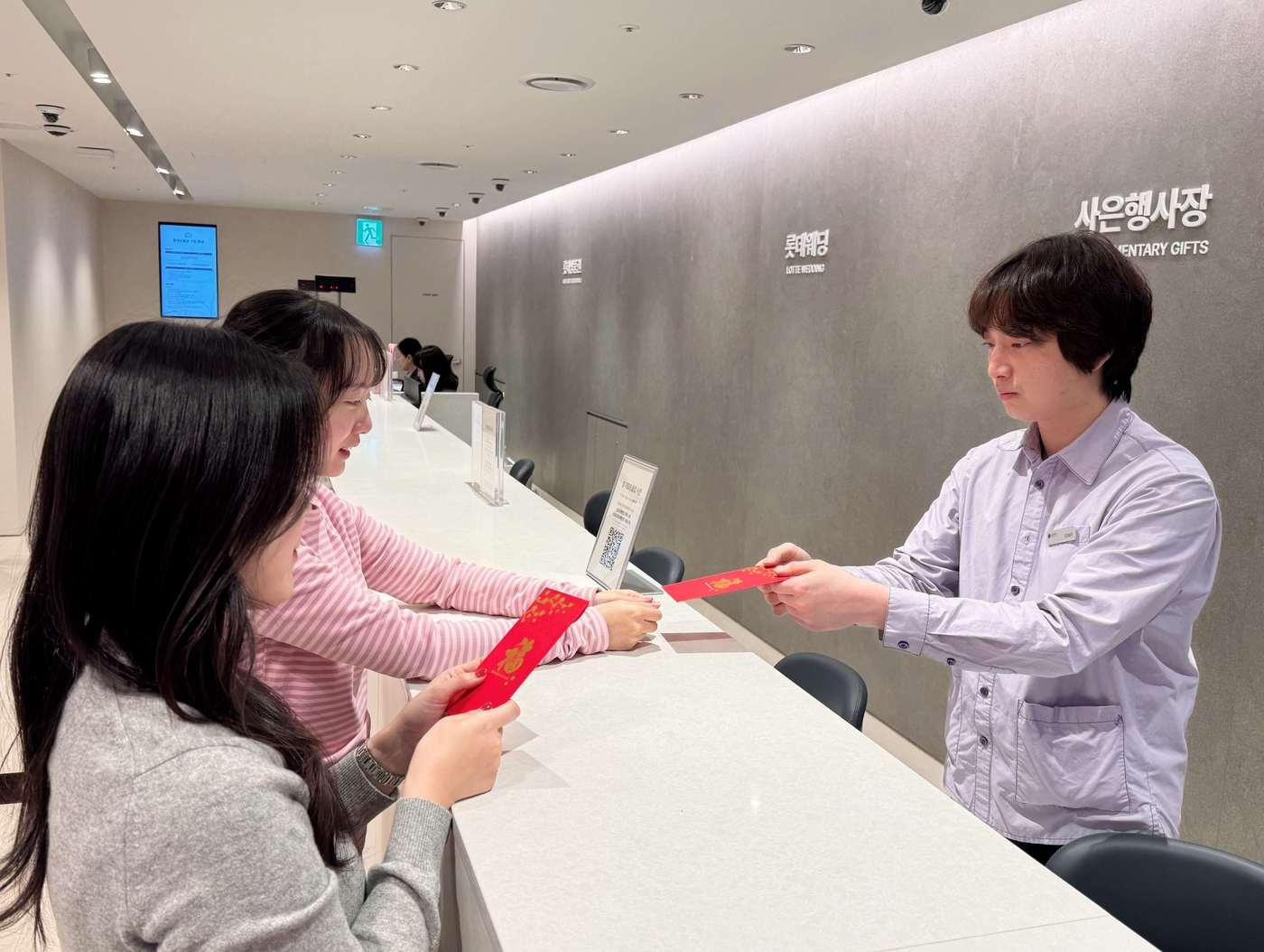 본문 이미지 - 본점 사은행사장에서 춘절 기념 홍바오(붉은 봉투)에 상품권을 증정하는 모습.(롯데백화점 제공)