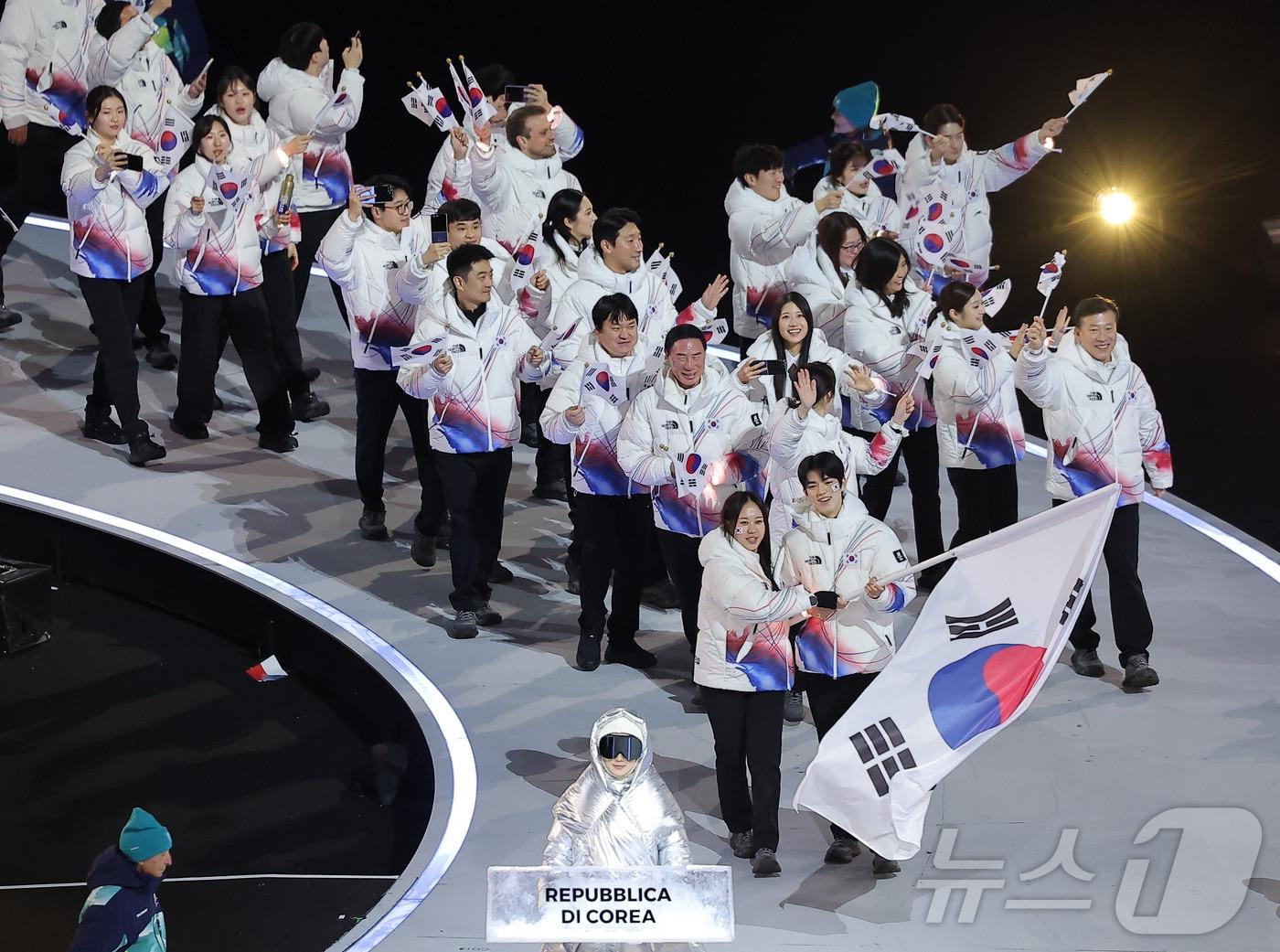 본문 이미지 - 대한민국 선수단 기수 차준환(피겨 스케이팅)과 박지우(스피드 스케이팅)가 6일 오후(현지시간) 이탈리아 밀라노 산시로 올림픽 스타디움에서 열린 2026 밀라노·코르티나담페초 동계올림픽대회 개회식에서 선수단을 이끌고 입장하고 있다. 2026.2.7 ⓒ 뉴스1 김성진 기자