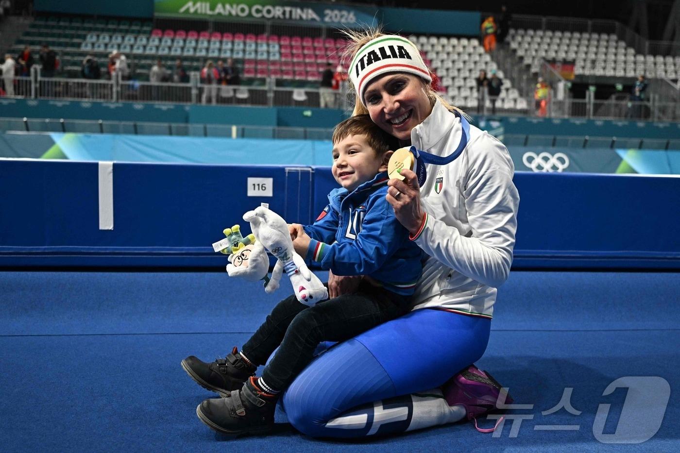본문 이미지 - 프란체스카 롤로브리지다(이탈리아)가 8일(한국시간) 열린 2026 밀라노 코르티나 동계 올림픽 스피드스케이팅 여자 3000m에서 금메달을 딴 뒤 아들 토마소와 함께 기뻐하고 있다. ⓒ AFP=뉴스1