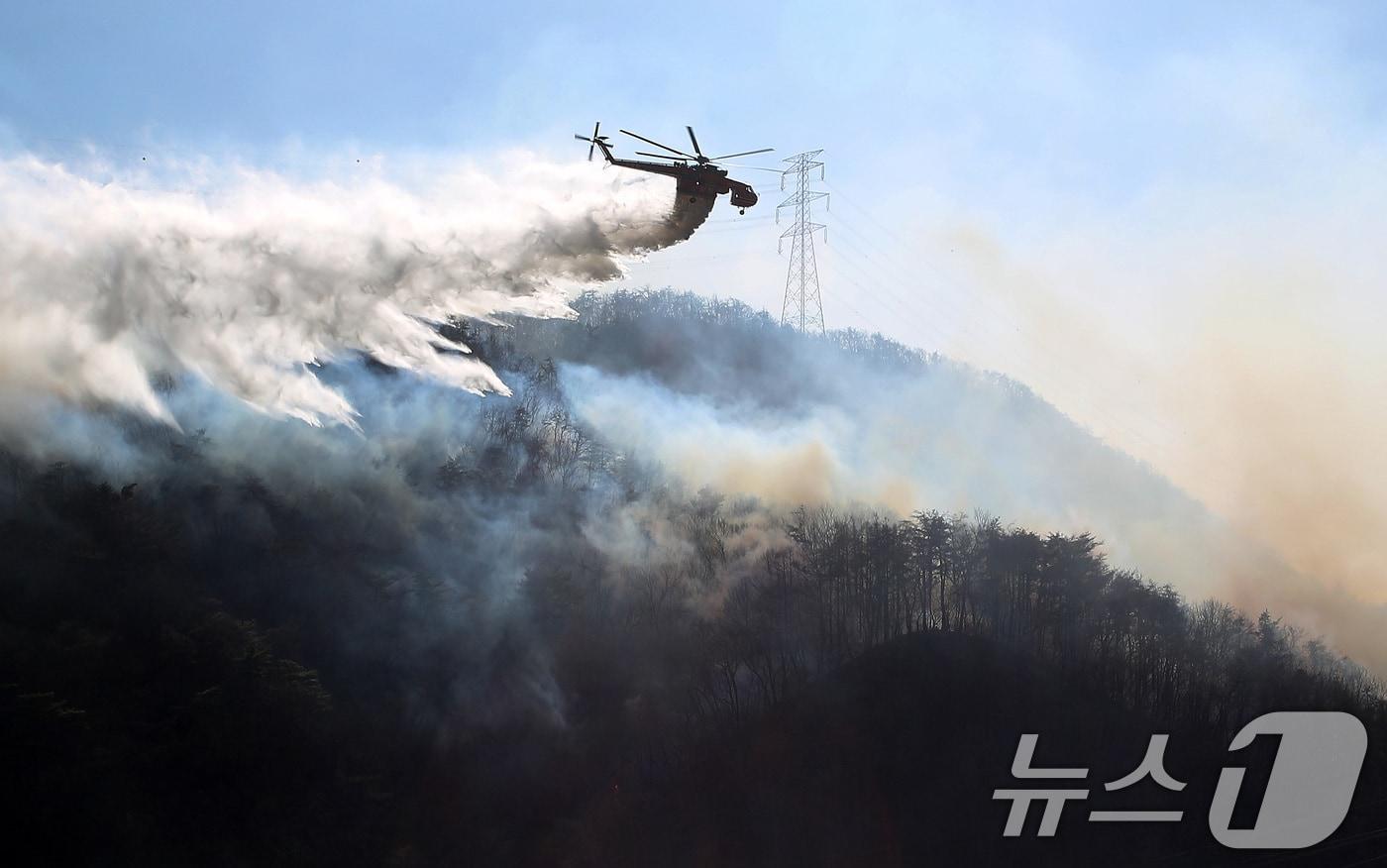 본문 이미지 - 8일 오전 경북 경주시 문무대왕면 산불이 강풍을 타고 주변으로 확산하는 가운데 산불 진화에 투입된 헬기가 송전탑 주변을 날아가며 산불을 진화하고 있다. 2026.2.8 ⓒ 뉴스1 공정식 기자