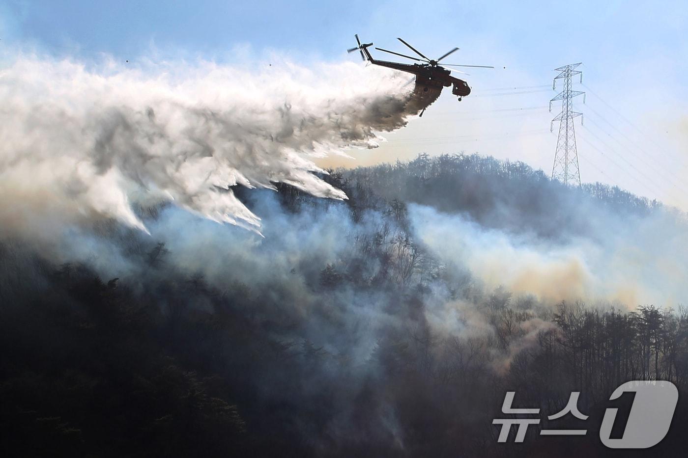본문 이미지 - 8일 오전 경북 경주시 문무대왕면 산불이 강풍을 타고 주변으로 확산하는 가운데 산불 진화에 투입된 헬기가 송전탑 주변을 날아가며 산불을 진화하고 있다. 2026.2.8 ⓒ 뉴스1 공정식 기자