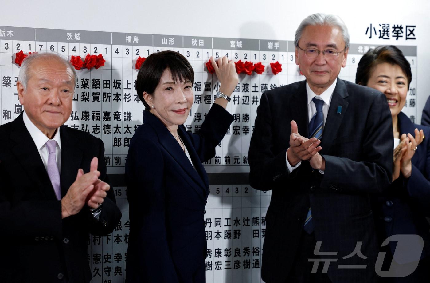 본문 이미지 - 8일 일본 중의원 선거에서 집권 자민당이 압승한 가운데, 다카이치 사나에 총리(왼쪽에서 두번째)가 도쿄 자민당 본부를 방문해 당선자에 빨간색 종이 장미를 올려놓고 있다. 2026.02.08 ⓒ 로이터=뉴스1