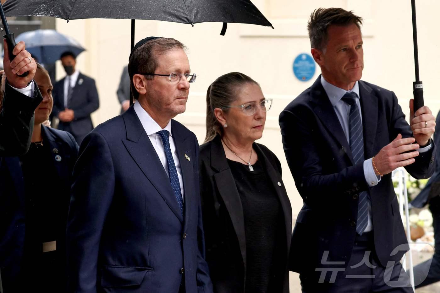 본문 이미지 - 9일(현지시간) 이스라엘 대통령 이츠하크 헤르초그(왼쪽)와 그의 부인 미할(가운데)이 크리스 민스 뉴사우스웨일스주 총리의 안내를 받으며 시드니 본다이 파빌리온에서 발생한 2025년 12월 14일 총격 사건 희생자들을 추모하기 위해 헌화하러 도착했다. 2026.02.09. ⓒ AFP=뉴스1 ⓒ News1 이정환 기자