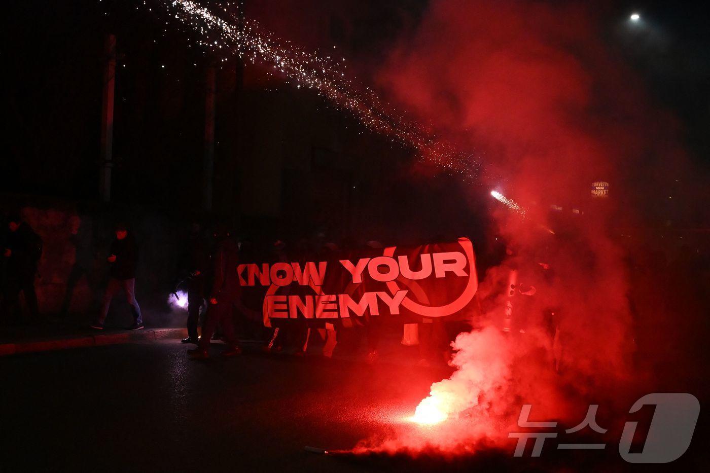 본문 이미지 - 7일(현지시간) 이탈리아 밀라노에서 열린 밀라노·코르티나 동계올림픽이 환경·경제·사회에 미치는 영향에 항의하는 시위대가 경찰관들을 향해 폭죽을 쏘고 있다. 2025.02.09. ⓒ AFP=뉴스1 ⓒ News1 이정환 기자