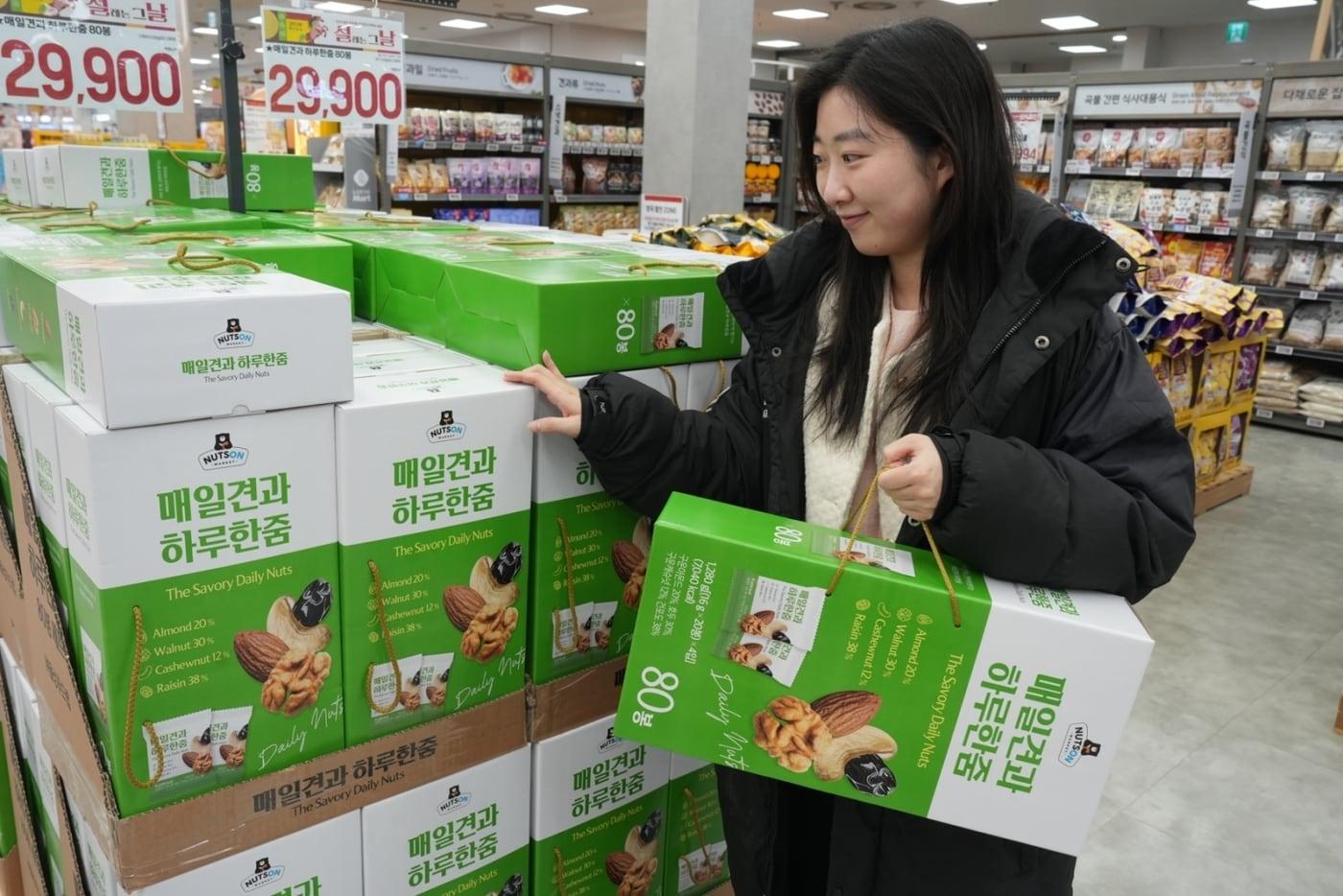 본문 이미지 - 서울 중구에 위치한 롯데마트 제타플렉스 서울역점에서 고객이 설 핸드캐리형 '매일견과 하루 한줌 80봉' 선물세트를 구매하고 있다.(롯데마트 제공) 