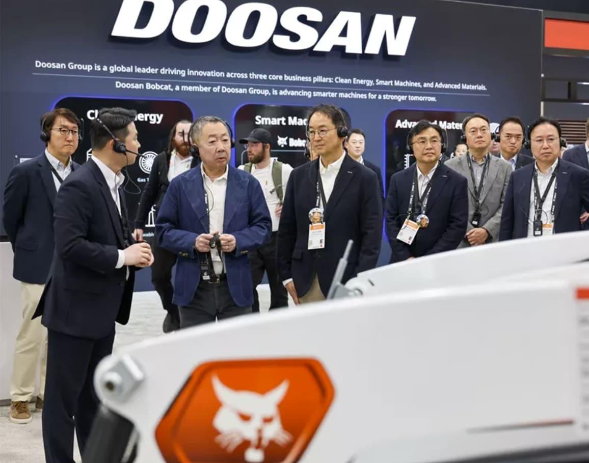 본문 이미지 - 박정원 두산그룹 회장(가운데)이 미국 라스베이거스 ‘콘엑스포 2026’ 현장을 찾아 두산밥캣의 미니트랙로더에 직접 탑승해 스캇 박 두산밥캣 부회장(맨 왼쪽) 설명을 듣고 있다.(두산그룹제공)