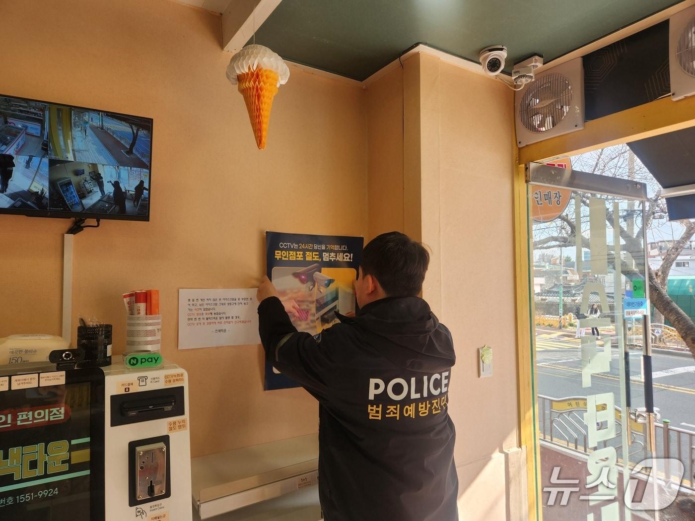 본문 이미지 - 울산경찰이 10일 무인 매장에 범죄 예방 홍보 포스터를 붙이고 있다.(울산경찰청 제공. 재판매 및 DB금지)/뉴스1