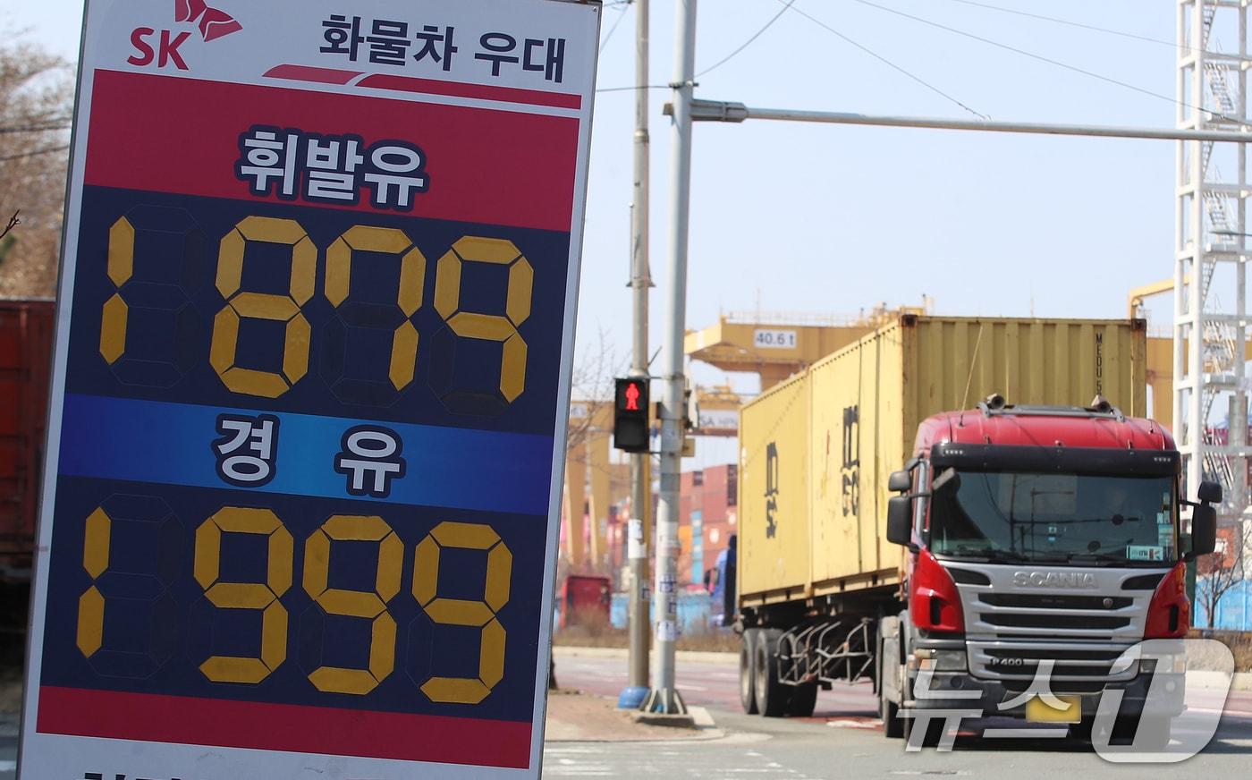 본문 이미지 - 중동 사태로 국제 유가가 급등하면서 유류비 부담이 커진 화물차 기사들이 어려움을 호소하고 있는 가운데 10일 경유 가격이 1999원으로 적혀 있는 부산 강서구 부산신항 인근 한 주유소 유가 안내판 뒤로 화물차들이 지나가고 있다. 2026.3.10 ⓒ 뉴스1 윤일지 기자