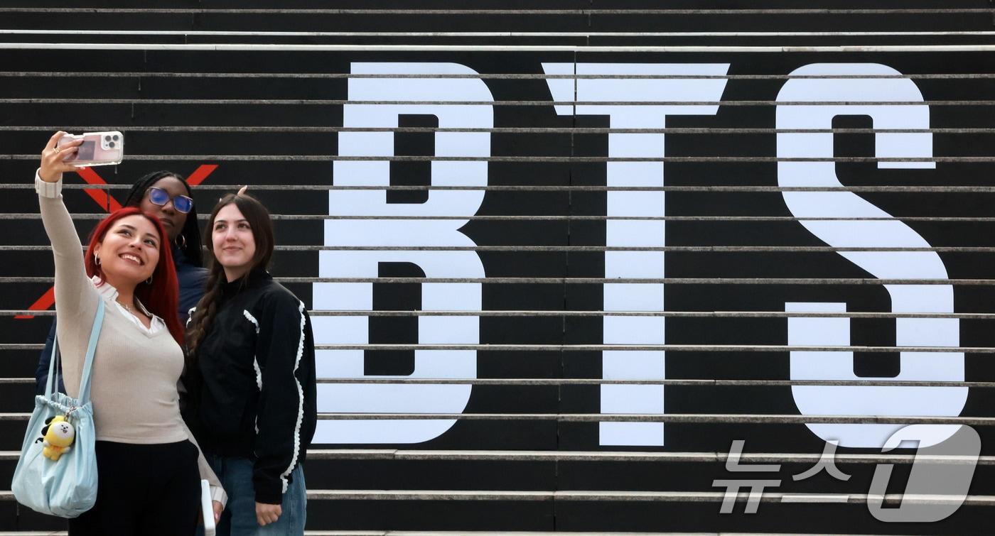 본문 이미지 - 방탄소년단의 컴백 라이브 공연을 열흘 앞둔 11일 서울 종로구 세종문화회관 계단에 마련된 방탄소년단 공연 홍보물 앞에서 외국인 관광객들이 기념촬영을 하고 있다. 2026.3.11 ⓒ 뉴스1 이호윤 기자