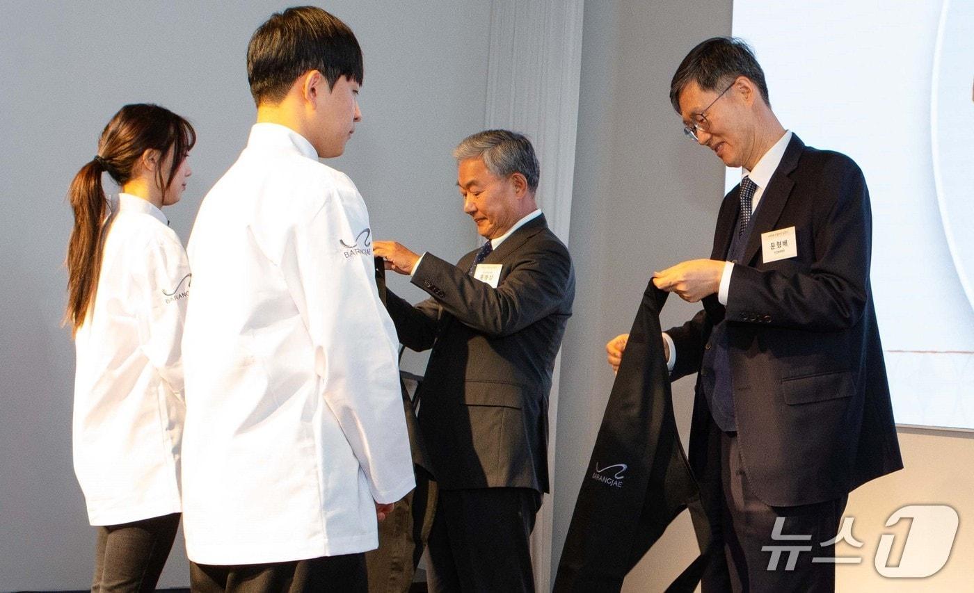 본문 이미지 - 지난 10일 평창 바랑재에서 진행된 바랑재드림키친 입학식에 문형배 전 헌법재판소 재판관과 홍봉성 라이나전성기재단 이사장이 참석해 참가 청년들에게 앞치마를 수여하고 있다./사진제공=라이나생명