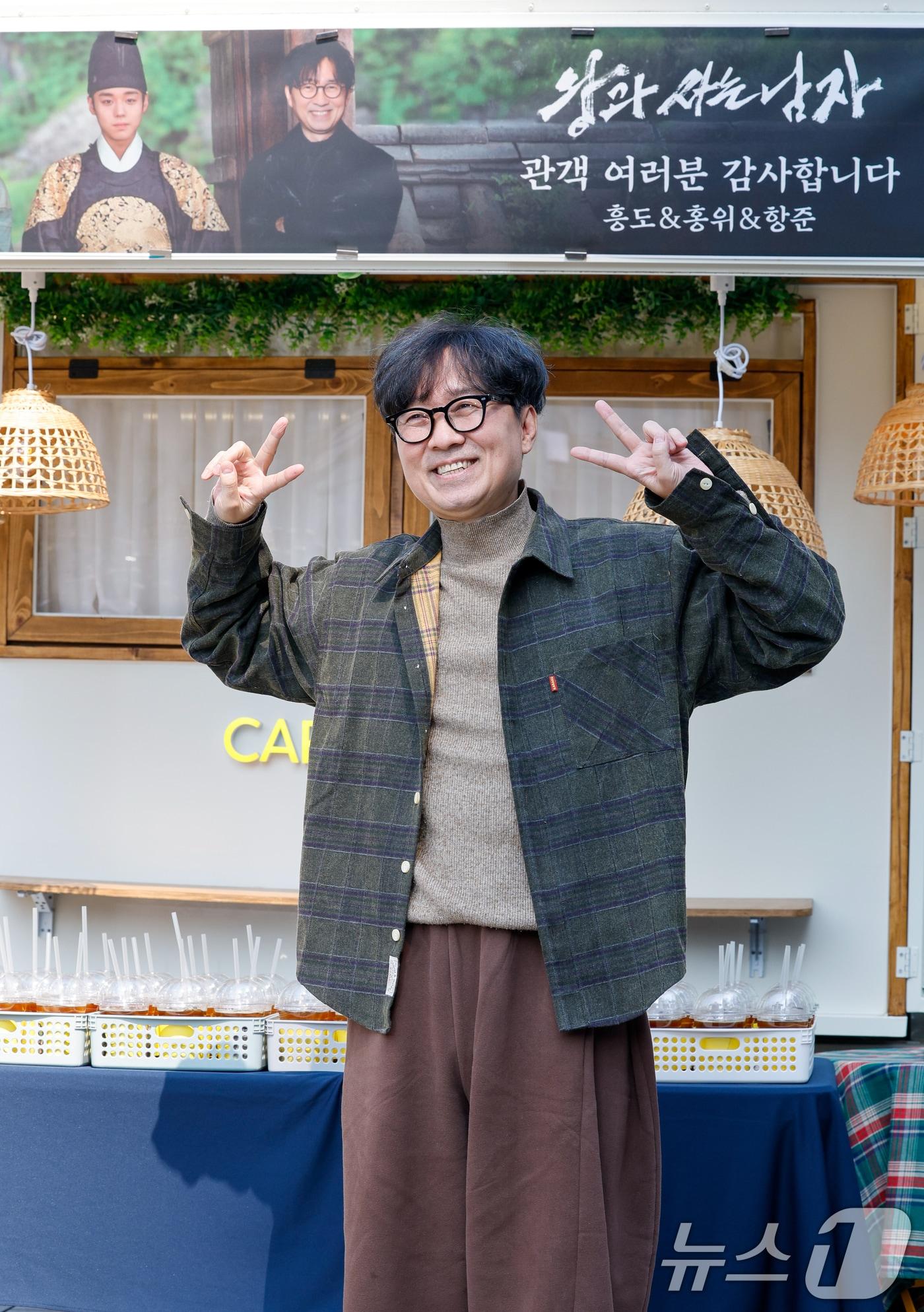 본문 이미지 - 영화 '왕과 사는 남자'의 장항준 감독이 12일 서울 중구 프레스센터 앞에서 1,200만 관객 돌파를 기념해 커피차를 마련, 팬들에게 커피를 나눠주기 전 포토타임을 갖고 있다. ⓒ 뉴스1 안은나 기자