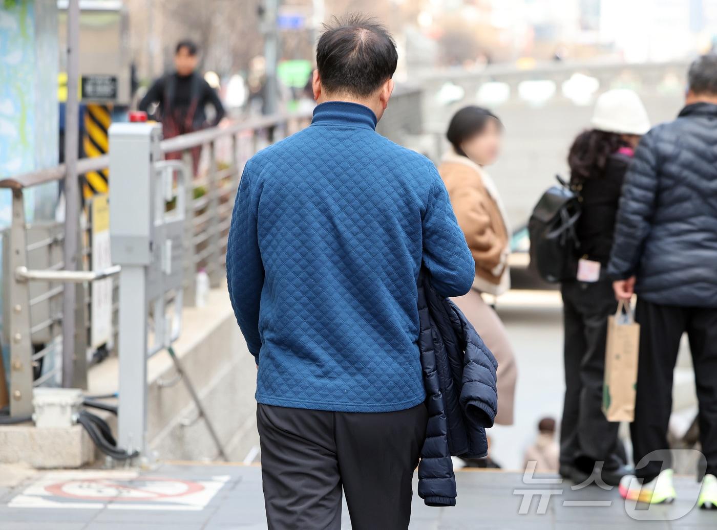 본문 이미지 - 일교차가 컸던 지난 12일 서울 종로구 청계천 입구에서 한 시민이 외투를 손에 든 채 발걸음을 옮기고 있다. 2026.3.12 ⓒ 뉴스1 김진환 기자