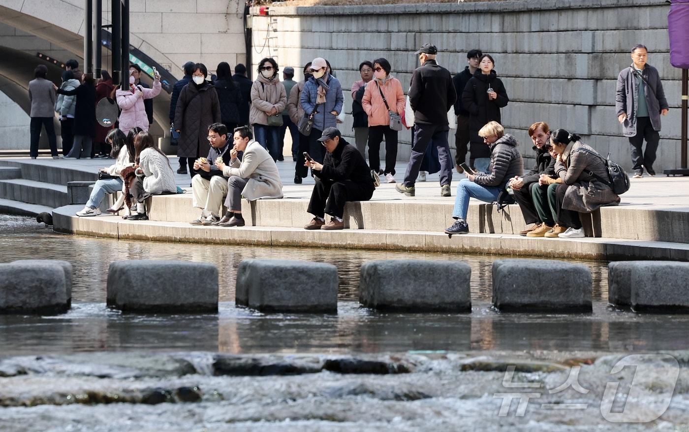 본문 이미지 - 서울의 낮 최고기온이 14도를 기록하는 등 포근한 날씨를 보인 12일 오후 서울 종로구 청계천을 찾은 시민들이 휴식을 취하고 있다. 2026.3.12 ⓒ 뉴스1 김진환 기자