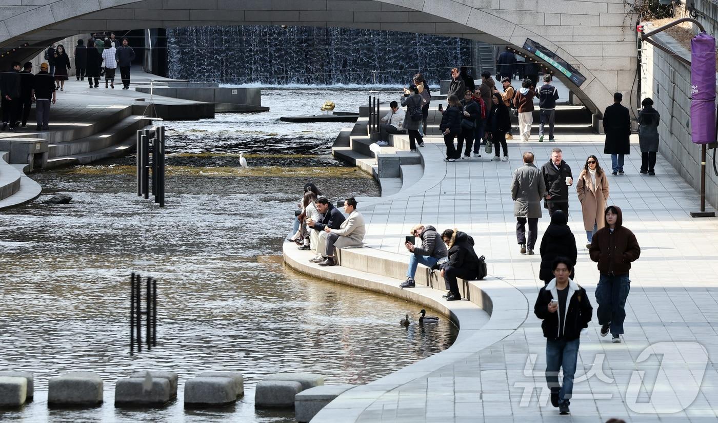본문 이미지 - 서울의 낮 최고기온이 14도를 기록하는 등 포근한 날씨를 보인 12일 오후 서울 종로구 청계천을 찾은 시민들이 휴식을 취하고 있다. 2026.3.12 ⓒ 뉴스1 김진환 기자