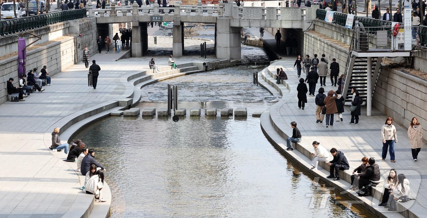 본문 이미지 - 서울의 낮 최고기온이 14도를 기록하는 등 포근한 날씨를 보인 12일 오후 서울 종로구 청계천을 찾은 시민들이 휴식을 취하고 있다. 2026.3.12 ⓒ 뉴스1 김진환 기자