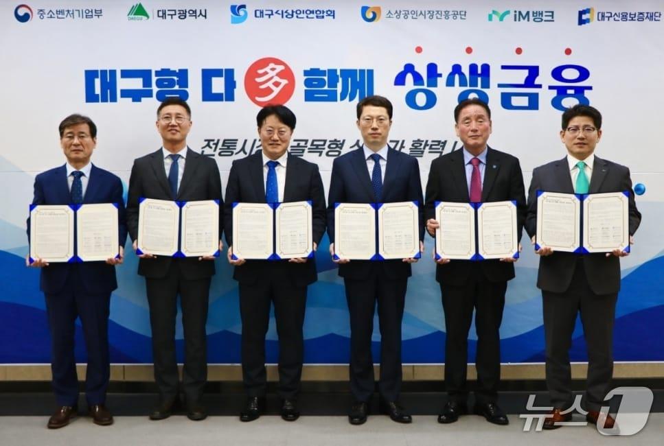본문 이미지 - 박진우 대구신용보증재단 이사장(왼쪽부터), 김현석 소상공인시장진흥공단 대구경북지역본부장, 정기환 대구경북지방중소벤처기업청장, 박기환 대구시 경제국장, 박재청 대구시상인연합회 회장, 류희장 iM뱅크 여신그룹장이 '대구형 다(多) 함께 상생금융 업무협약'을 체결한 후 협약서를 펼쳐 보이고 있다.(대구신보 제공, 재판매 및 DB 금지)