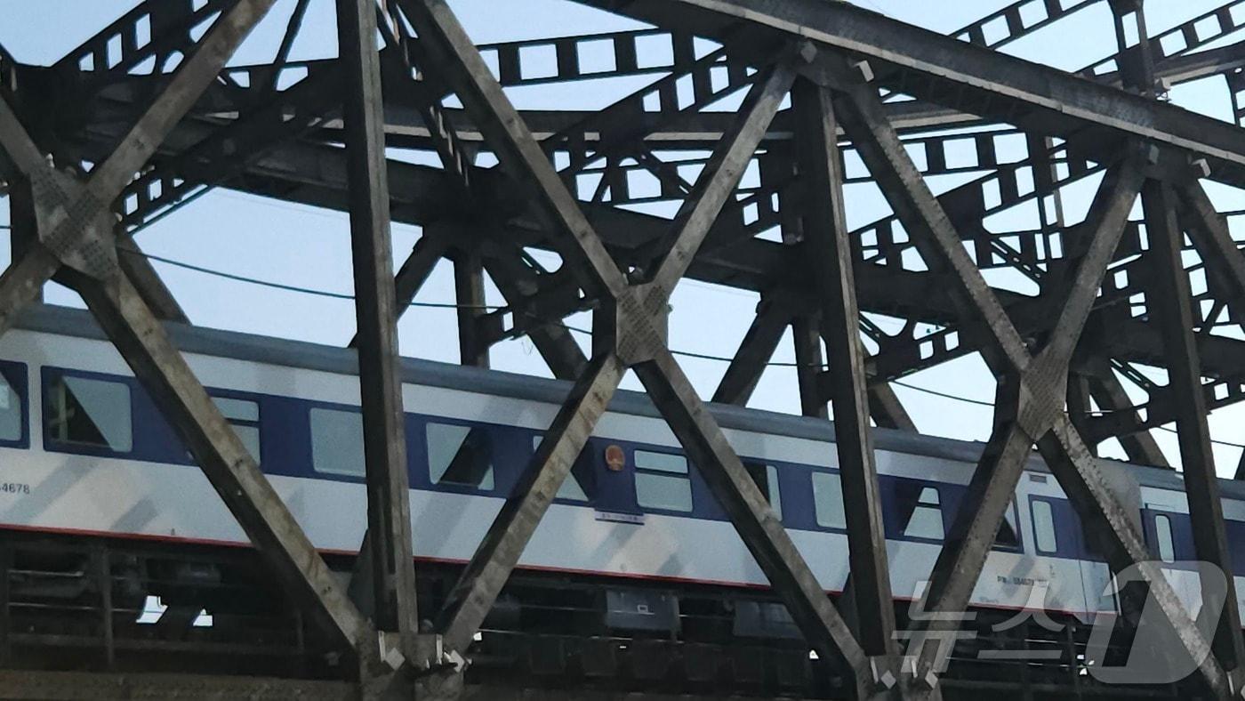 본문 이미지 - 13일 오전 10시 단둥역을 출발한 국제 여객 열차가 압록강철교를 지나고 있다. 파란색 열차는 전일 오후 베이징에서 출발한 열차다. 2026.3.13