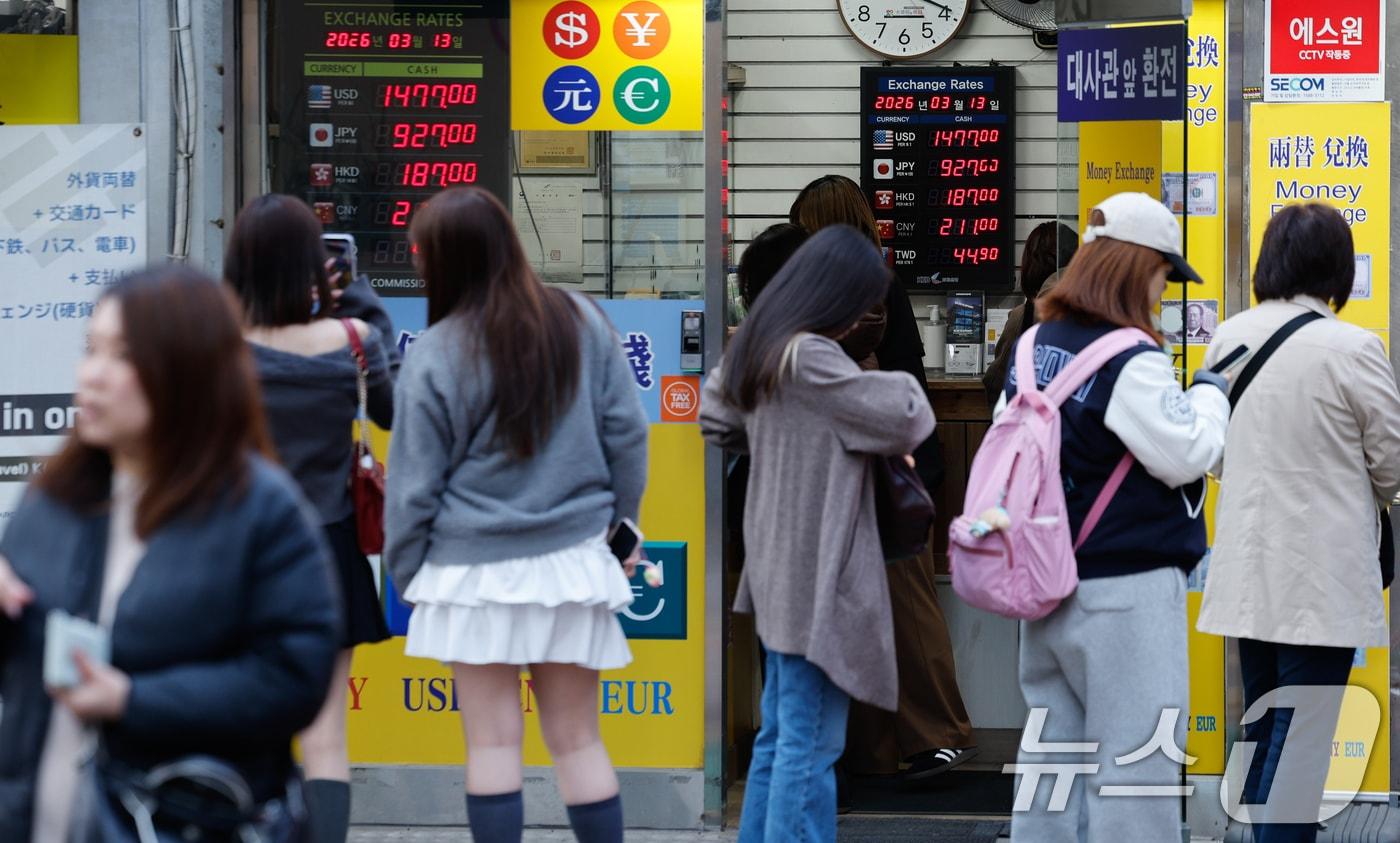 본문 이미지 - 국제 유가 급등에 환율이 이틀째 오르고 있는 13일 서울 중구 명동거리의 환전소에서 외국인 관광객들이 환전하기 위해 줄을 서 있다. 2026.3.13 ⓒ 뉴스1 안은나 기자