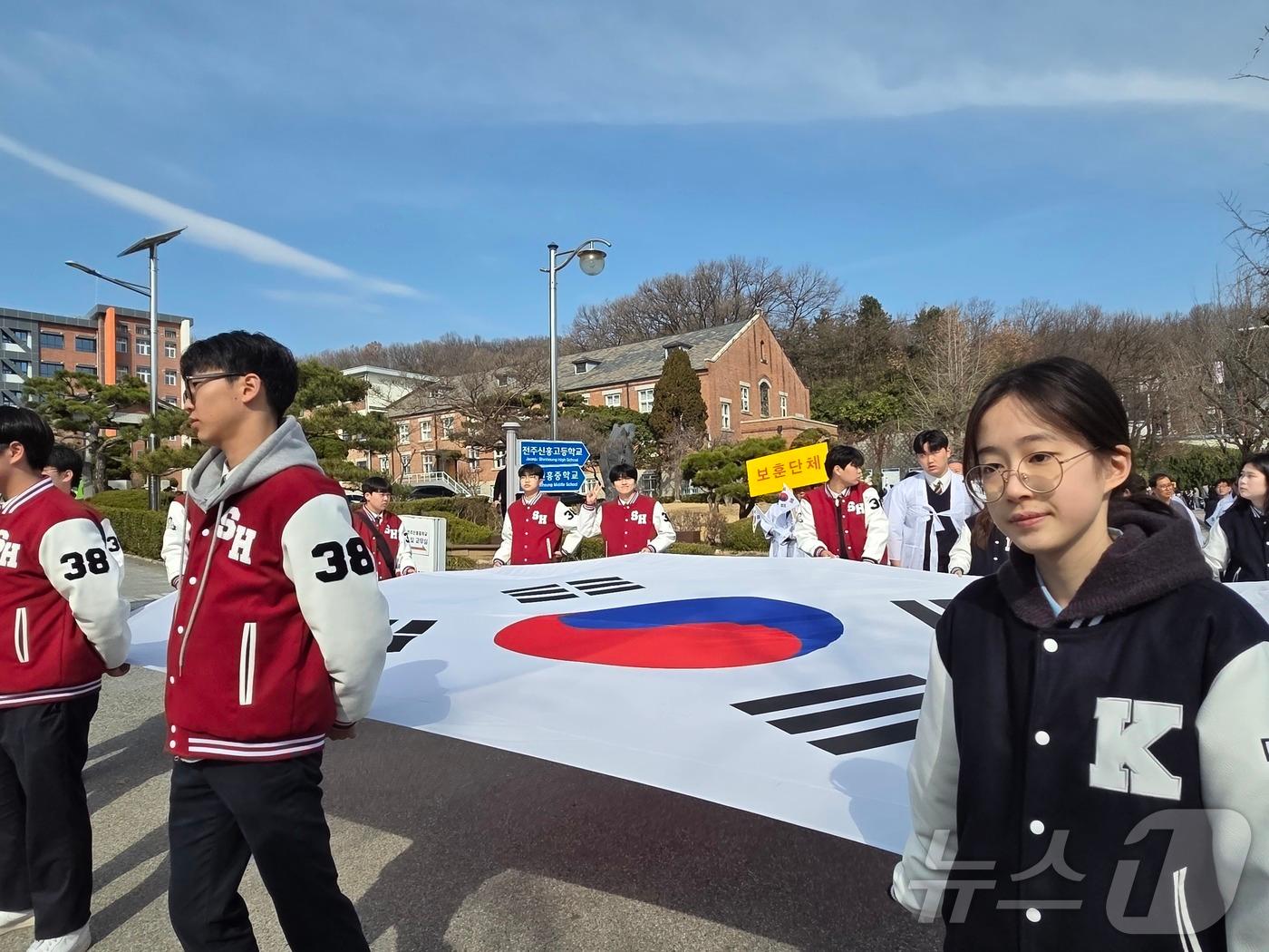 본문 이미지 - 14일 오전 전북 전주시 중화산동 전주신흥고등학교에서 열린 '3·13 만세운동' 재현행사에 참여한 학생들과 시민들이 태극기를 들고 행진하고 있다. 2026.3.14 ⓒ 뉴스1 장수인 기자