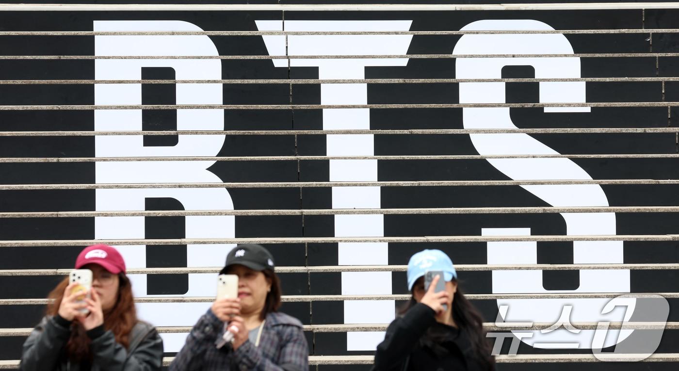 본문 이미지 - 서울 종로구 세종문화회관 계단에 마련된 방탄소년단(BTS)의 컴백 라이브 공연 홍보물 앞에서 외국인 관광객이 기념촬영을 하고 있다. 약 3년 9개월 만에 컴백하는 방탄소년단(BTS)의 공연은 오는 21일 오후 8시 광화문광장에서 ‘BTS 컴백 라이브: 아리랑(ARIRANG)’이라는 타이틀로 개최된다. 2026.3.15 ⓒ 뉴스1 김명섭 기자