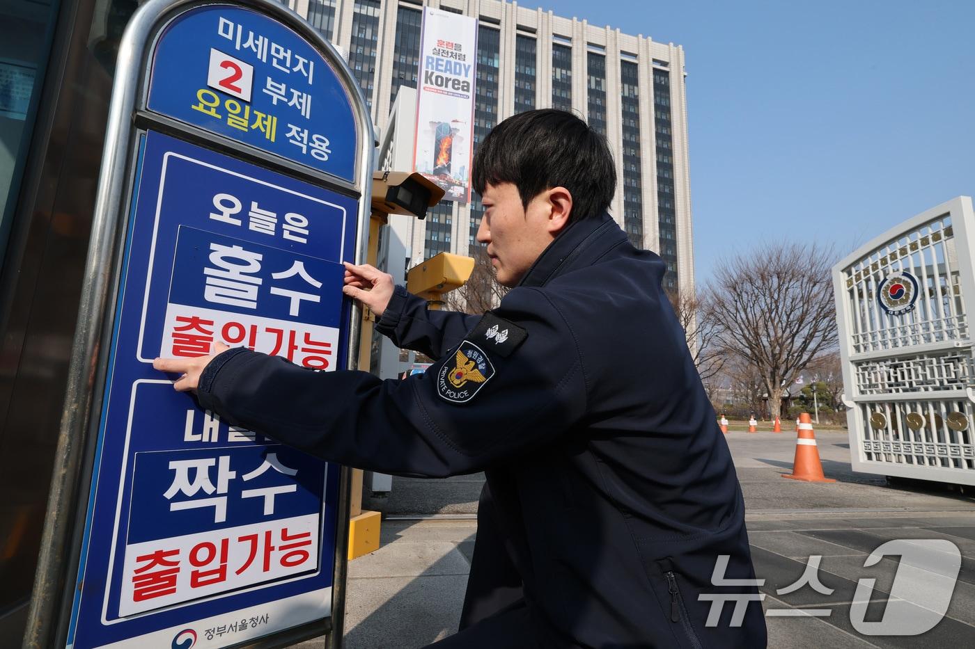 본문 이미지 - 서울 종로구 정부서울청사에서 관계자가 입구에 차량 2부제 실시 안내판을 설치하고 있다. 2026.3.17 ⓒ 뉴스1 임세영 기자