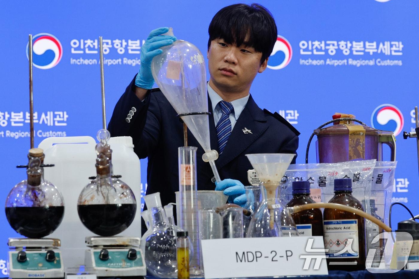 본문 이미지 - 17일 인천 중구 인천공항본부세관 수출입통관청사에서 직원이 국내 항정신성 마약 MDMA(엑스터시) 제조 시설 적발 및 유통일당 검거와 관련, 압수품을 들어 보이고 있다. 관세청 인천공항세관은 마약류 원료물질을 밀수입해 국내에서 MDMA를 제조한 베트남 국적 마약조직원 3명을 마약류 관리에 관한 법률 위반 혐의로 검거, 구속 송치했다고 밝혔다. 이들이 밀수입한 원료는 사프롤, 글리시디에이트 등 5.4kg으로 이는 시가 8억8천만원(29,430명 동시 투약분) 상당에 달한다. 2026.3.17 ⓒ 뉴스1 안은나 기자