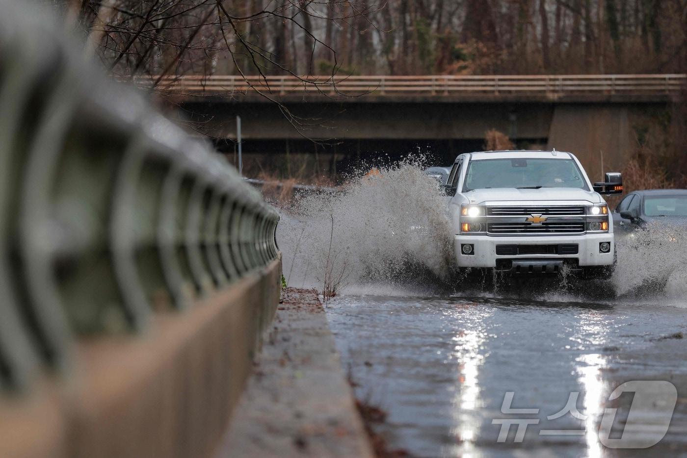 본문 이미지 - 16일(현지시간) 미국 메릴랜드주 캐빈존에서 차량이 침수된 도로를 지나고 있다. 이날 강한 폭풍으로 워싱턴DC와 메릴랜드 일부 지역에 강풍과 뇌우가 발생하고 토네이도 경보가 내려졌다. 2026.03.16. ⓒ AFP=뉴스1