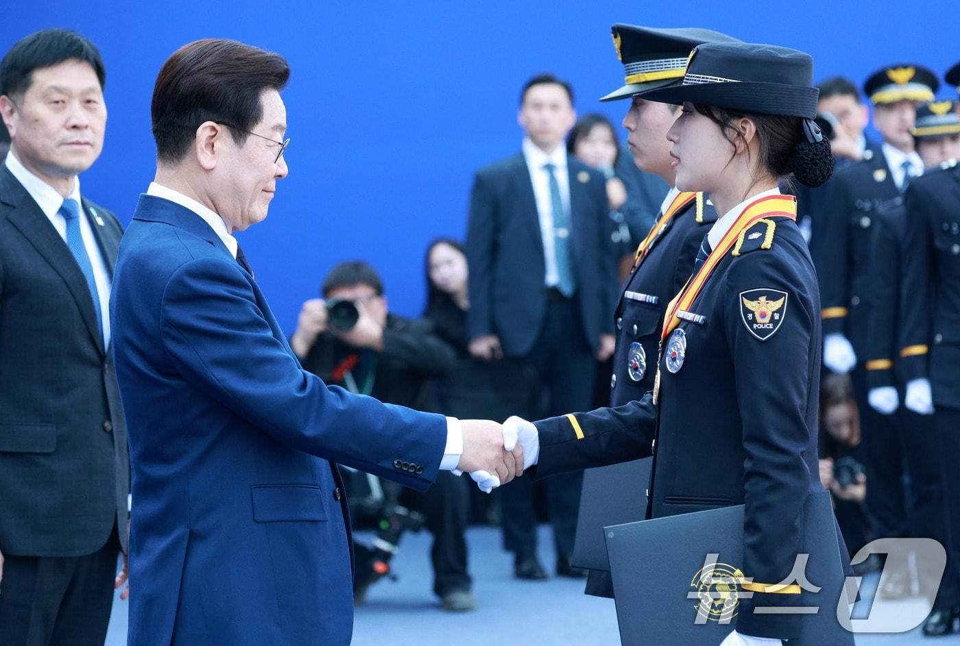 본문 이미지 - 이재명 대통령이 17일 충남 아산시 경찰대학에서 열린 신임 경찰 경위·경감 임용식에서 동이정 경위에게 상장을 수여한 후 악수하고 있다. (청와대통신사진기자단) 2026.3.17 ⓒ 뉴스1 이재명 기자