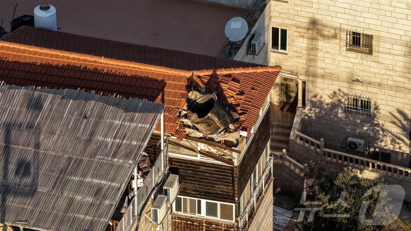 본문 이미지 - 16일 미·이스라엘과 이란 간 충돌 속에 동예루살렘의 한 건물 옥상에 떨어진 이란 미사일 잔해가 드론 카메라에 포착됐다. 2026.03.16. ⓒ 로이터=뉴스1