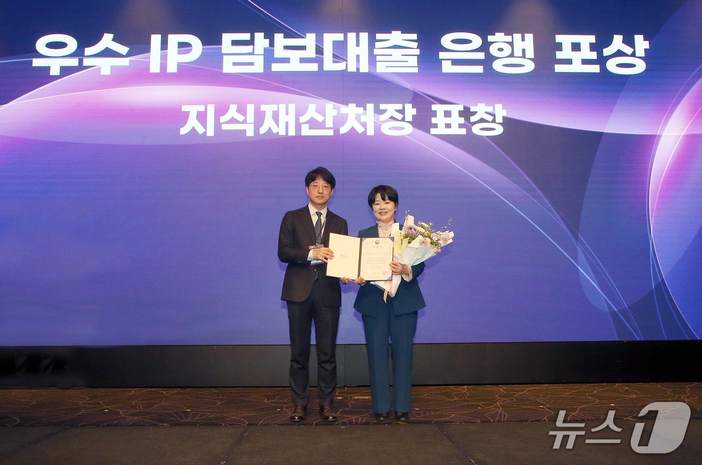 본문 이미지 - 17일 서울 서초구 소재 엘타워에서 열린 2026년 제1회 IP금융 협의회에서 '우수 IP 담보대출 은행 포상' 수상 후 윤혜영 신한은행 영업추진1부 본부장(오른쪽)과 유용신 지식재산처 지식재산거래과장이 기념촬영하는 모습. 2026.03.17 / 사진제공=신한은행