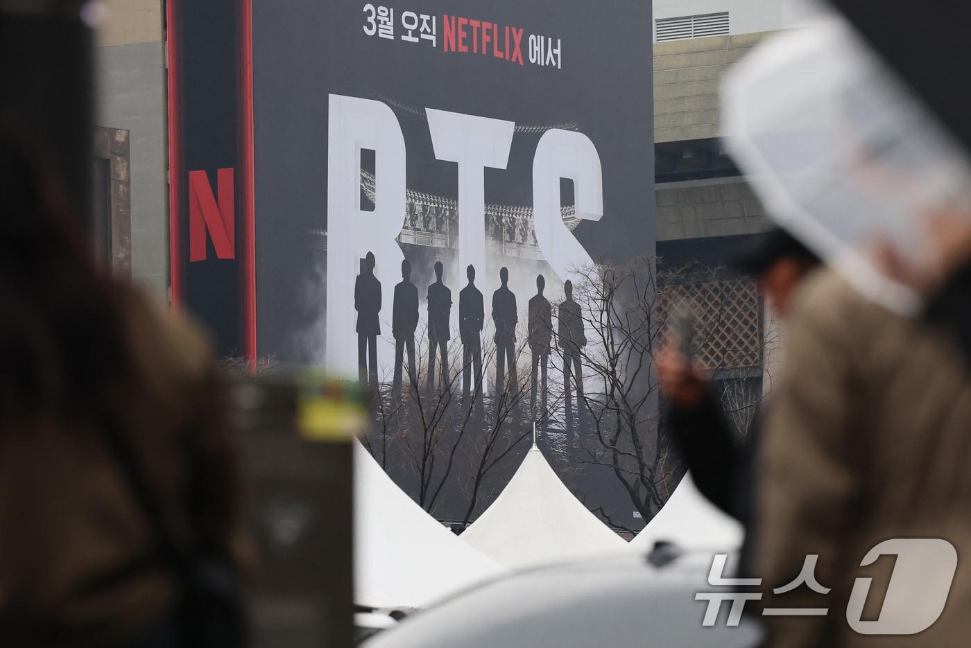 본문 이미지 - 방탄소년단(BTS) 완전체 컴백 공연을 사흘 앞둔 18일 서울 광화문광장에서 외국인 팬들이 컴백 공연을 알리는 전광판 광고를 스마트폰으로 촬영하고 있다. 2026.3.18 ⓒ 뉴스1 오대일 기자