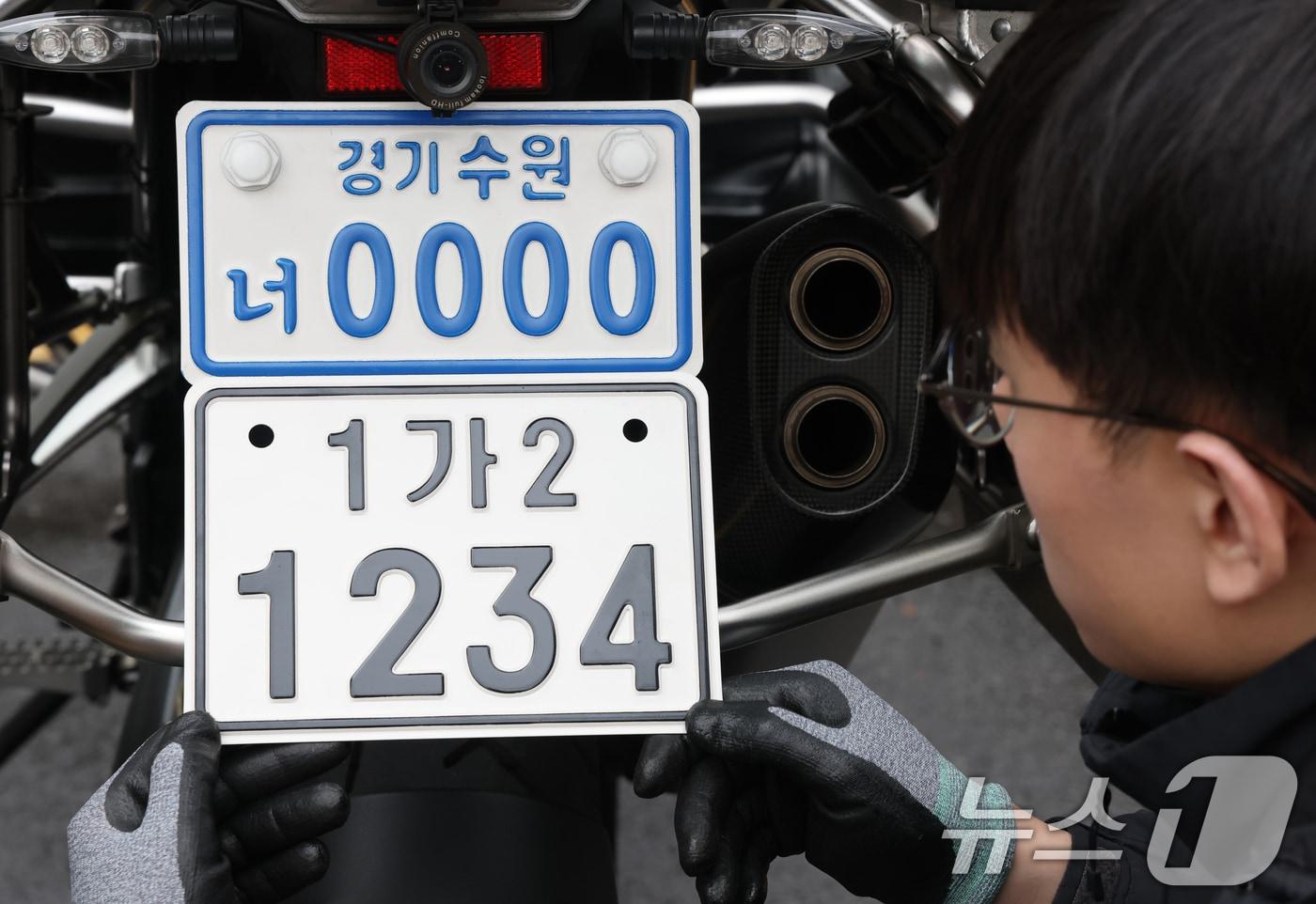 본문 이미지 - 이륜자동차 전국 번호판 제도 시행을 이틀 앞둔 18일 경기 수원시 권선구 수원도시공사 번호판제작소에서 관계자가 번호판 교체 시연을을 하고 있다. 새롭게 도입되는 번호판은 기존 번호판에 표시되던 지역명 표기가 폐지되며 크기가 확대되고 디자인이 변경된다. ⓒ 뉴스1 김영운 기자