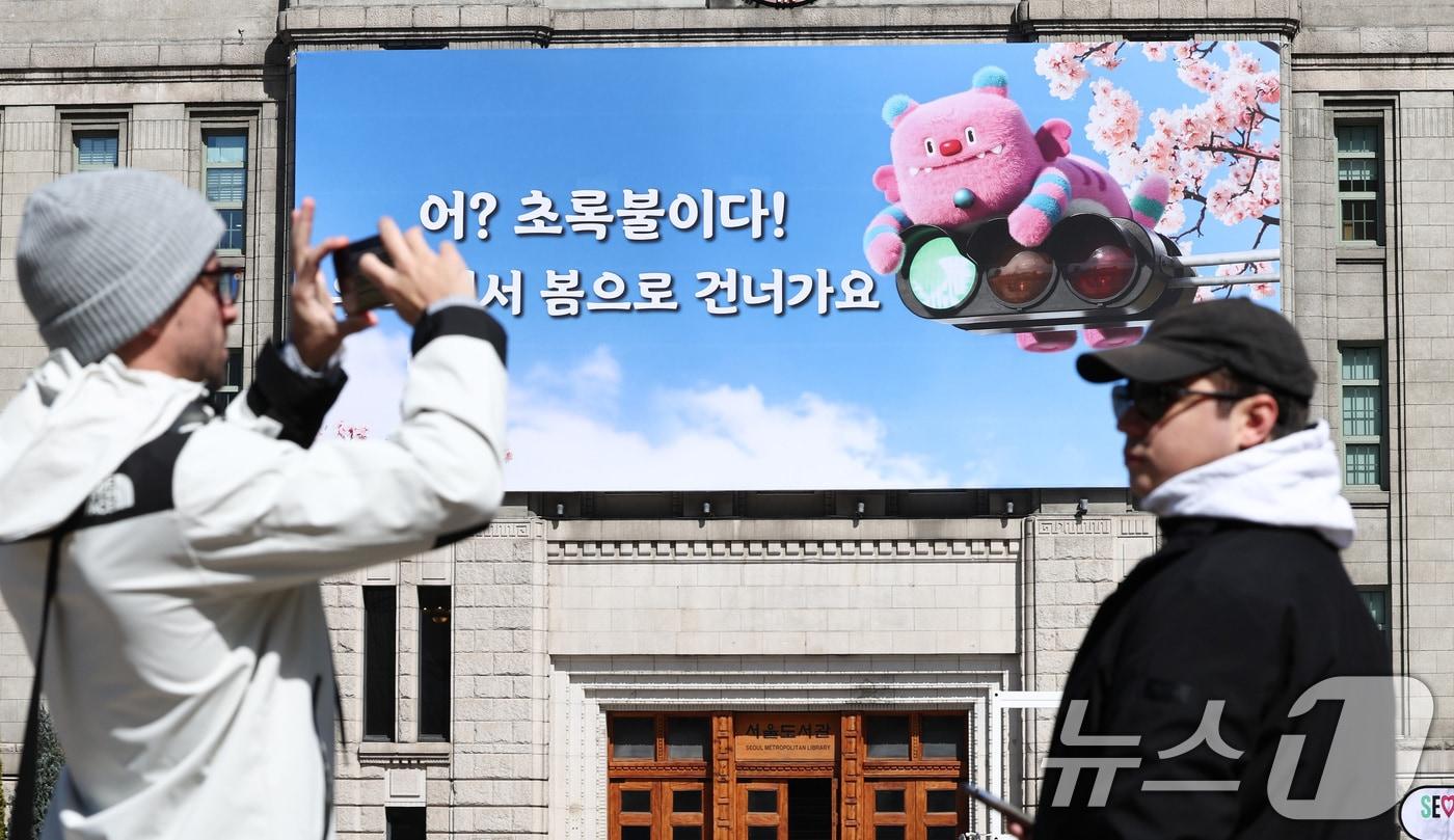 본문 이미지 - 19일 서울 중구 서울도서관 외벽에 ‘어? 초록불이다! 우리, 어서 봄으로 건너가요’라는 문구가 적힌 서울꿈새김판이 걸려 있다. 2026.3.19 ⓒ 뉴스1 최지환 기자