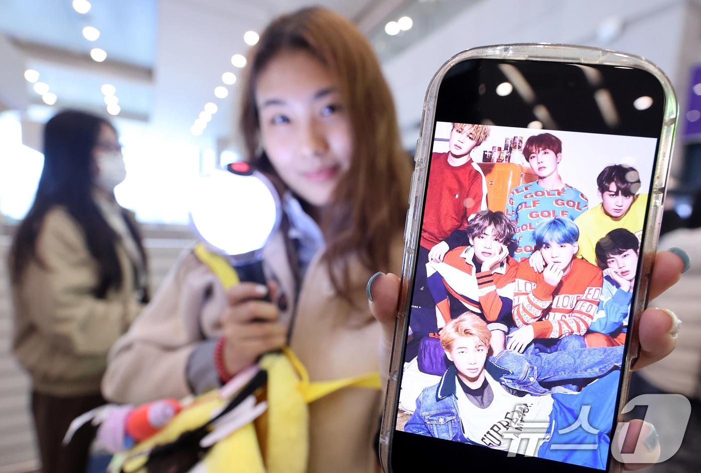 본문 이미지 - 19일 인천국제공항에서 BTS 팬클럽 ‘아미’인 중국인 클로이(20)가 입국하며 아미밤(방탄소년단 공식 응원봉)을 들어 보이고 있다. 오는 21일 서울 광화문광장에서 열리는 BTS 컴백 공연을 관람하기 위해 전 세계 ‘아미’(BTS 팬)들이 속속 한국을 찾고 있다. 2026.3.19 ⓒ 뉴스1 박지혜 기자