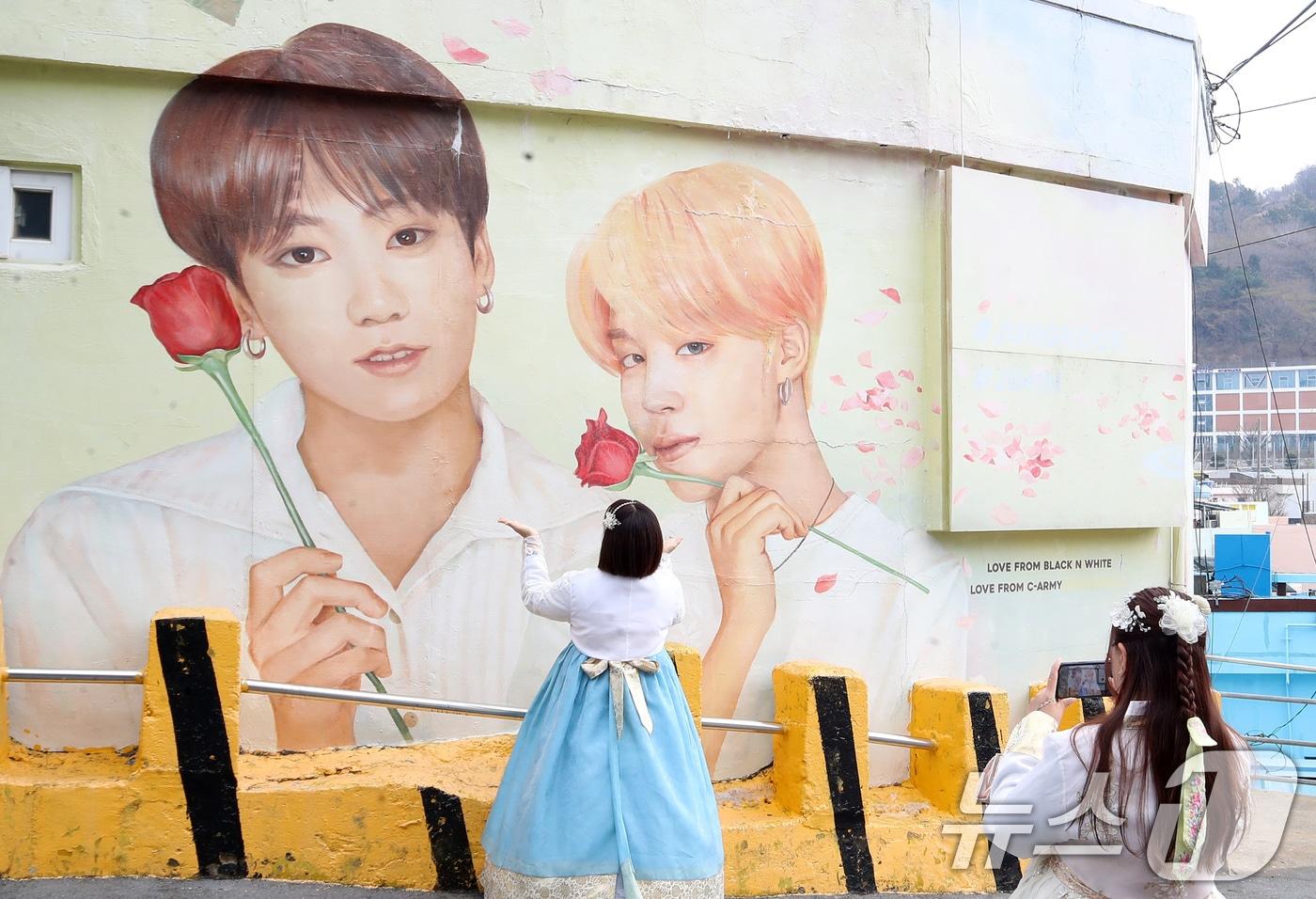 본문 이미지 - 방탄소년단(BTS) 컴백 공연을 이틀 앞둔 19일 부산 서구 감천문화마을에서 외국인 관광객들이 부산이 고향인 BTS 멤버 정국·지민이 그려진 대형 벽화를 배경으로 기념촬영을 하고 있다. 2026.3.19 ⓒ 뉴스1 윤일지 기자