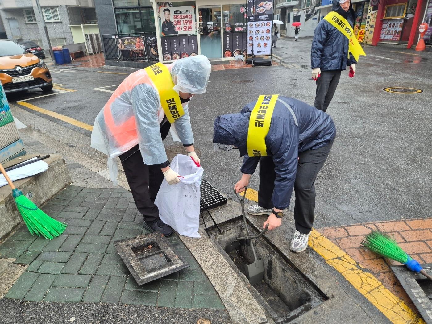 본문 이미지 - 직원들이 빗물받이에 쌓인 이물질 제거 작업을 하고 있다.(노원구 제공)