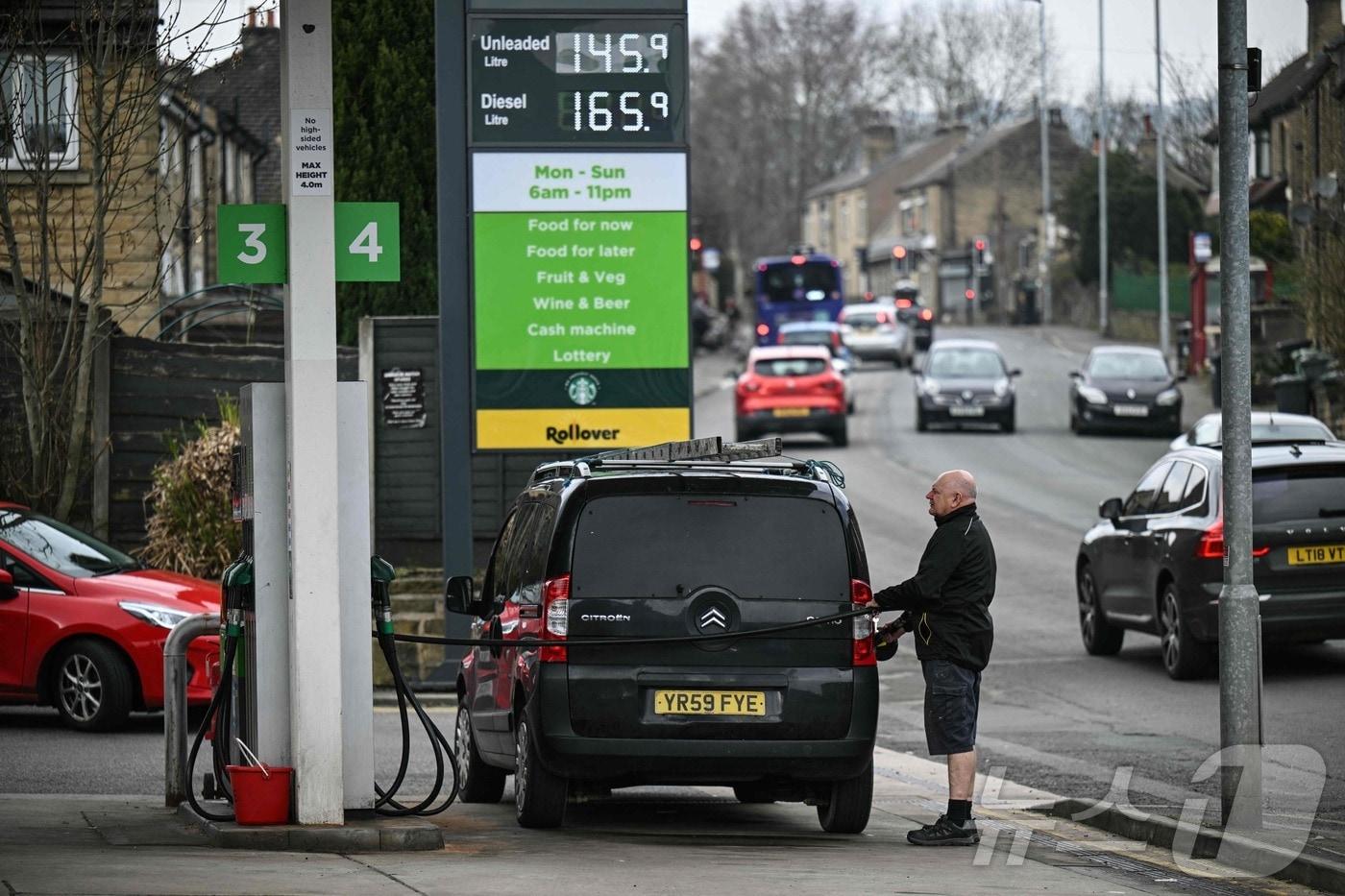 본문 이미지 - 영국 북부 허더즈필드 교외 밀른스브리지의 한 주유소에서 19일(현지시간) 한 고객이 차량에 연료를 주입하고 있다.2026.03.19.ⓒ AFP=뉴스1