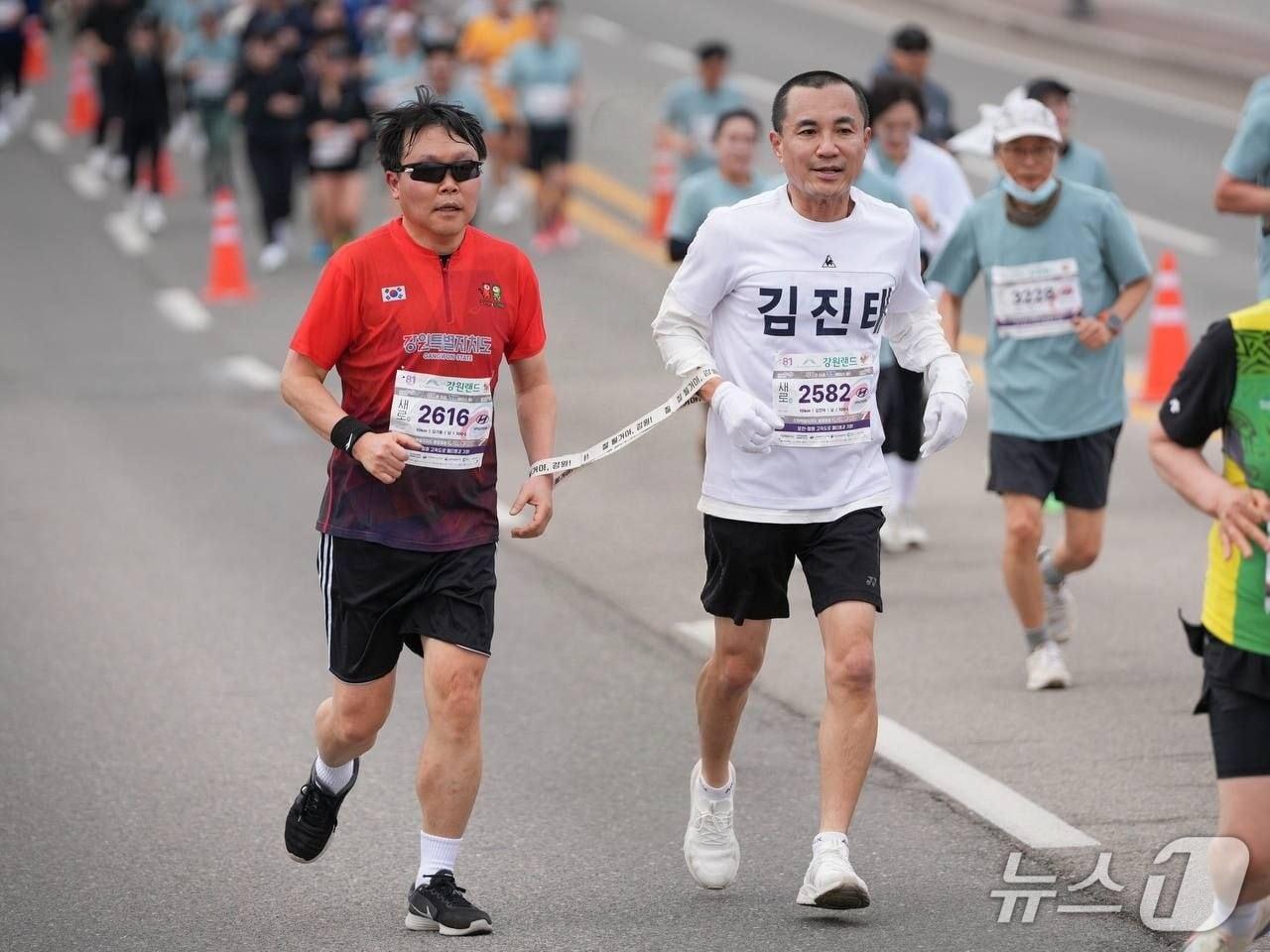 본문 이미지 - 김진태 강원특별자치도지사가 1일 열린 제27회 강원특별자치도민 건강달리기대회에서 시각장애인 러너가 안전하게 달릴 수 있도록 방향을 제시하고 속도를 조절하는 '가이드 러너' 역할을 맡아 10㎞ 전 구간을 완주했다.(강원도 제공. 재판매 및 DB금지)/뉴스1