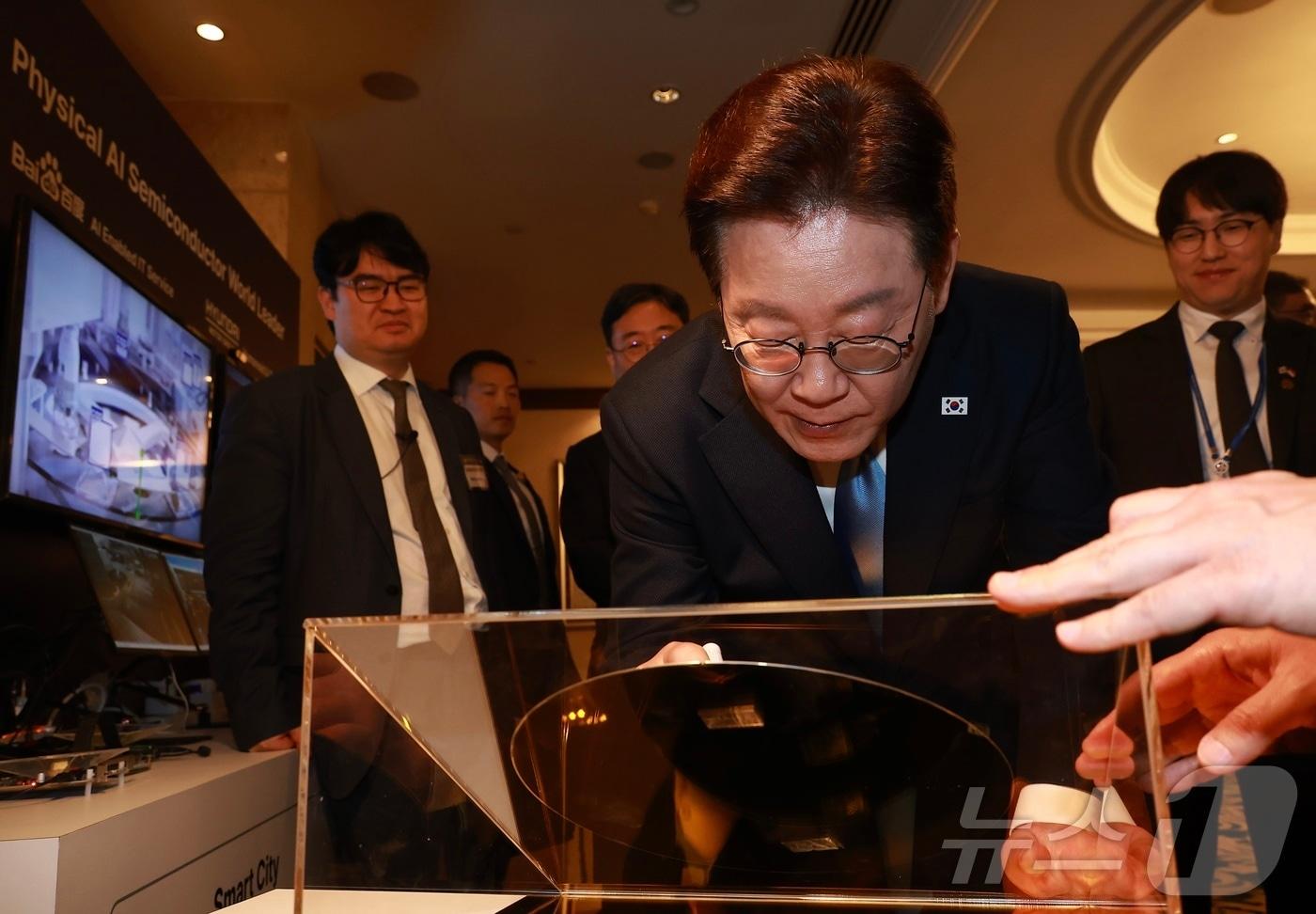 본문 이미지 - 이재명 대통령이 2일(현지시간) 싱가포르 한 호텔에서 열린 한·싱가포르 AI 커넥트 서밋 종료 후 전시 부스에서 웨이퍼에 서명하고 있다. 2026.3.2 ⓒ 뉴스1 허경 기자