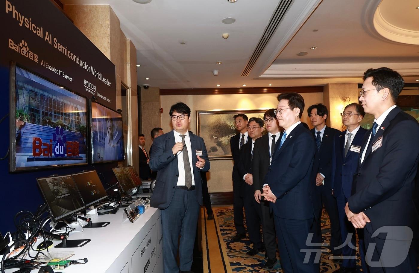 본문 이미지 - 이재명 대통령이 싱가포르 한 호텔에서 열린 한·싱가포르 AI 커넥트 서밋 종료 후 전시 업체 관계자로부터 AI 반도체 제품 상용화 사례에 대한 설명을 듣고 있다. 2026.3.2 ⓒ 뉴스1 허경 기자