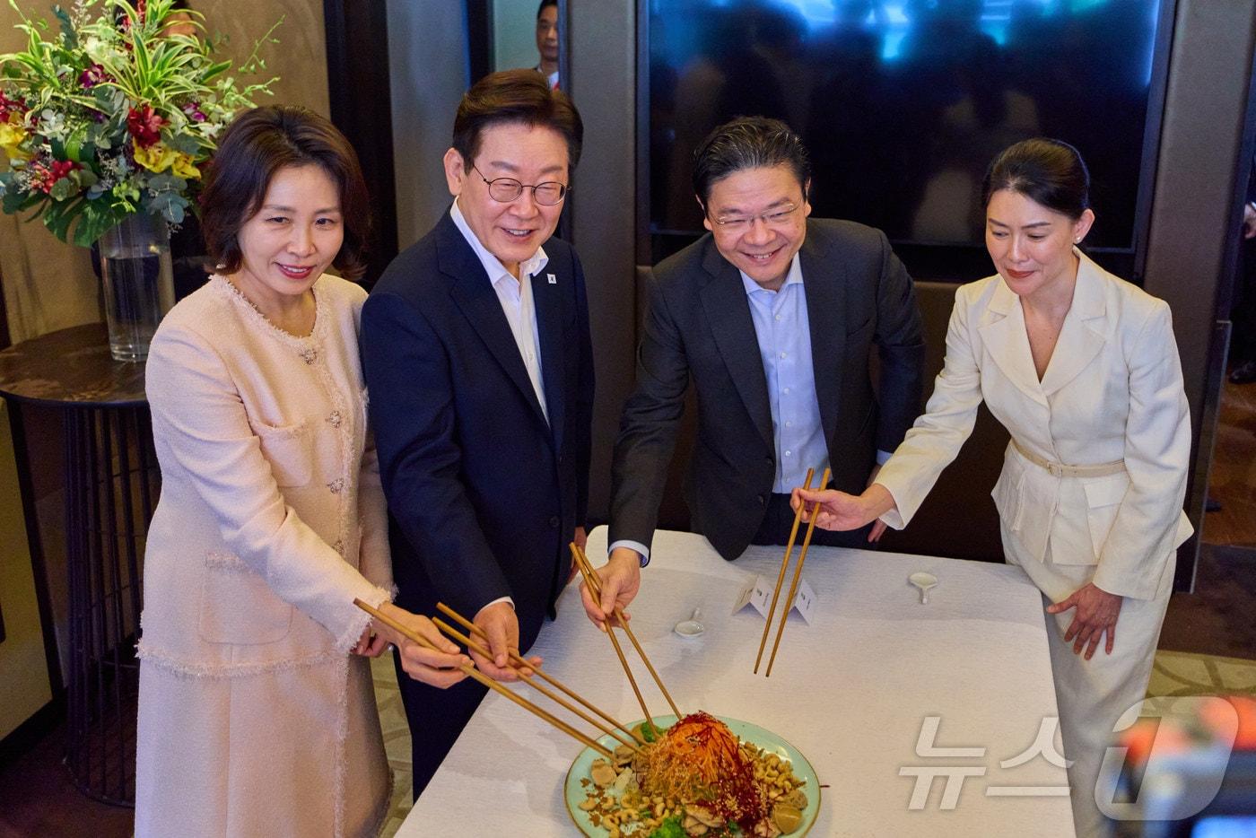 본문 이미지 - 이재명 대통령과 김혜경 여사, 로렌스 웡 싱가포르 총리, 루 즈 루이 여사가 2일(현지시간) 싱가포르 한 호텔에서 열린 친교 오찬에서 생선회 샐러드 ‘유생’을 함께 섞고 있다. (공동취재) 2026.3.2 ⓒ 뉴스1 허경 기자