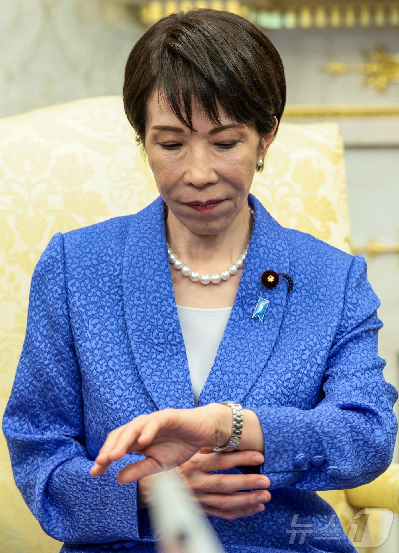 본문 이미지 - 다카이치 사나에 일본 총리가 19일(현지시간) 워싱턴DC 백악관에서 도널드 트럼프 미국 대통령과의 정상회담 중 잠시 시계를 들여다보고 있다. 이날 다카이치 총리는 납북된 일본인 피해자에 대한 관심을 촉구하는 파란 리본 배지를 달고 미일 정상회담에 임해 눈길을 끌었다. 2026.03.19. ⓒ 로이터=뉴스1