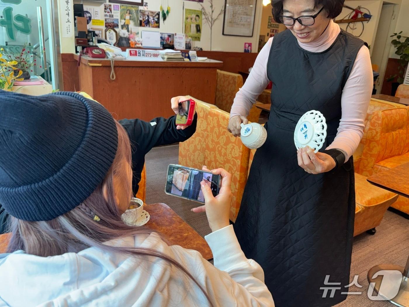 본문 이미지 - 대만에서 온 아미인 미화와 유미. BTS 멤버인 뷔가 사용했던 찻잔의 사진을 찍고 있다.. 2026.3.20 ⓒ 뉴스1 권준언 기자