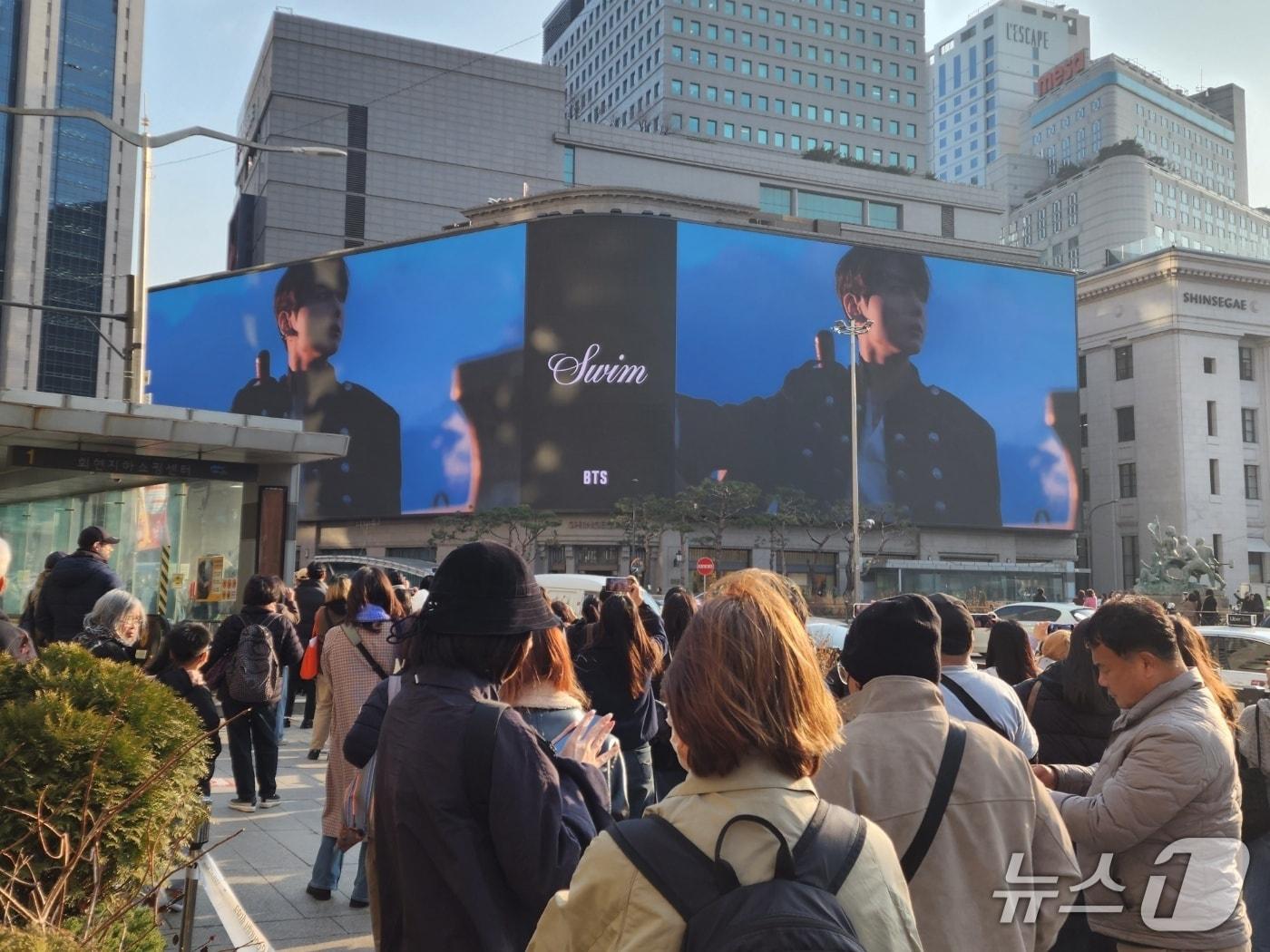 본문 이미지 - 20일 서울 명동 신세계스퀘어에 뜬 방탄소년단(BTS)의 신곡 'SWIM' 뮤직비디오를 찍기 위해 관광객들이 모여 있다. 2026.03.20/ⓒ 뉴스1 권진영 기자