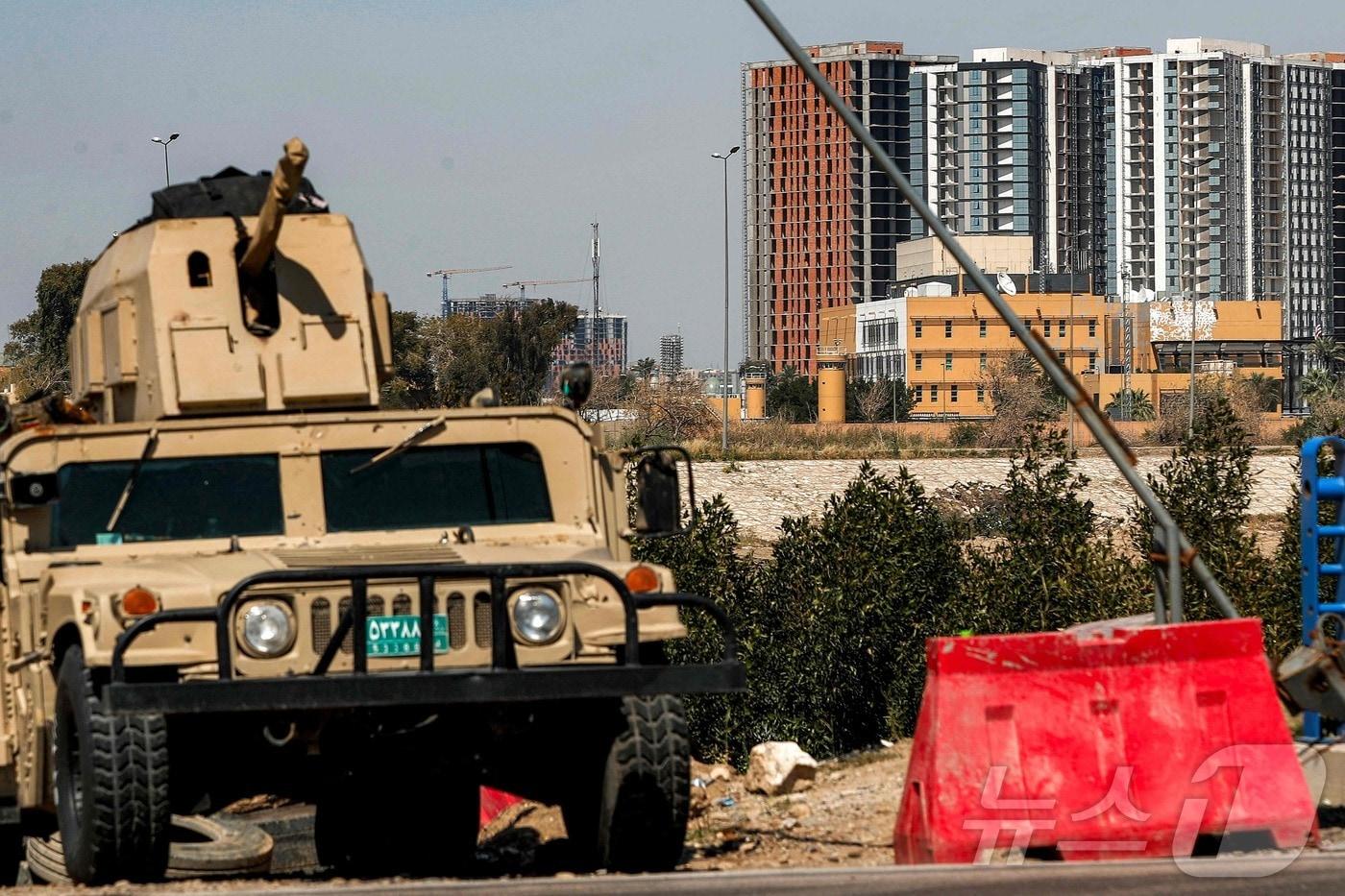 본문 이미지 - 이라크 육군의 험비 군용차량이 18일(현지시간) 바그다드의 요새화된 '그린 존' 내 티그리스 강변에 배치돼 미국 대사관 본부(오른쪽)를 보호하고 있다. 2026.03.18. ⓒ AFP=뉴스1