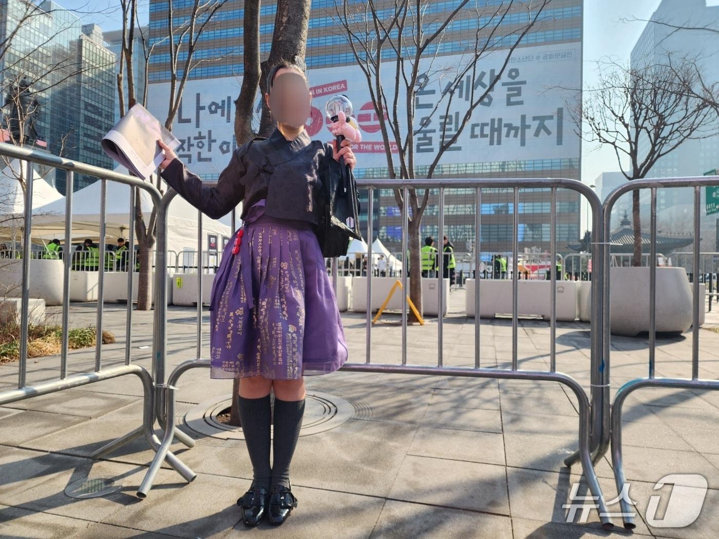 본문 이미지 - 21일 서울 광화문 광장에서 BTS 컴백 공연을 기다리고 있는 팬 이유아나리나 수르지오(15)가 아미봉과 BTS 특집 호외를 들고 서 있다. 2026.03.21/ⓒ 뉴스1 권진영 기자